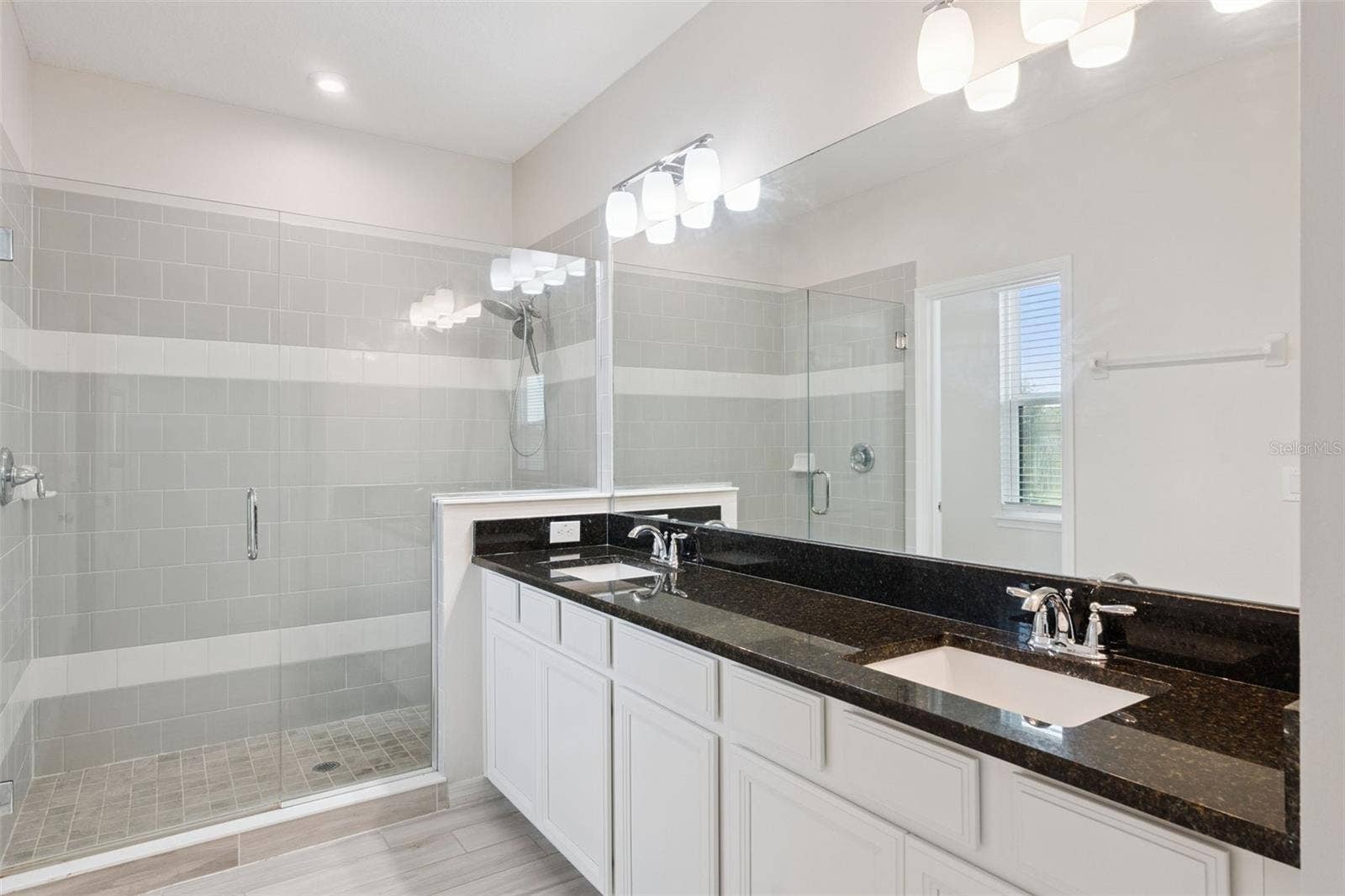 Primary Bathroom  Primary bath showcases a large glass-enclosed tiled shower alongside the dual-sink vanity, creating a bright and functional ensuite retreat.