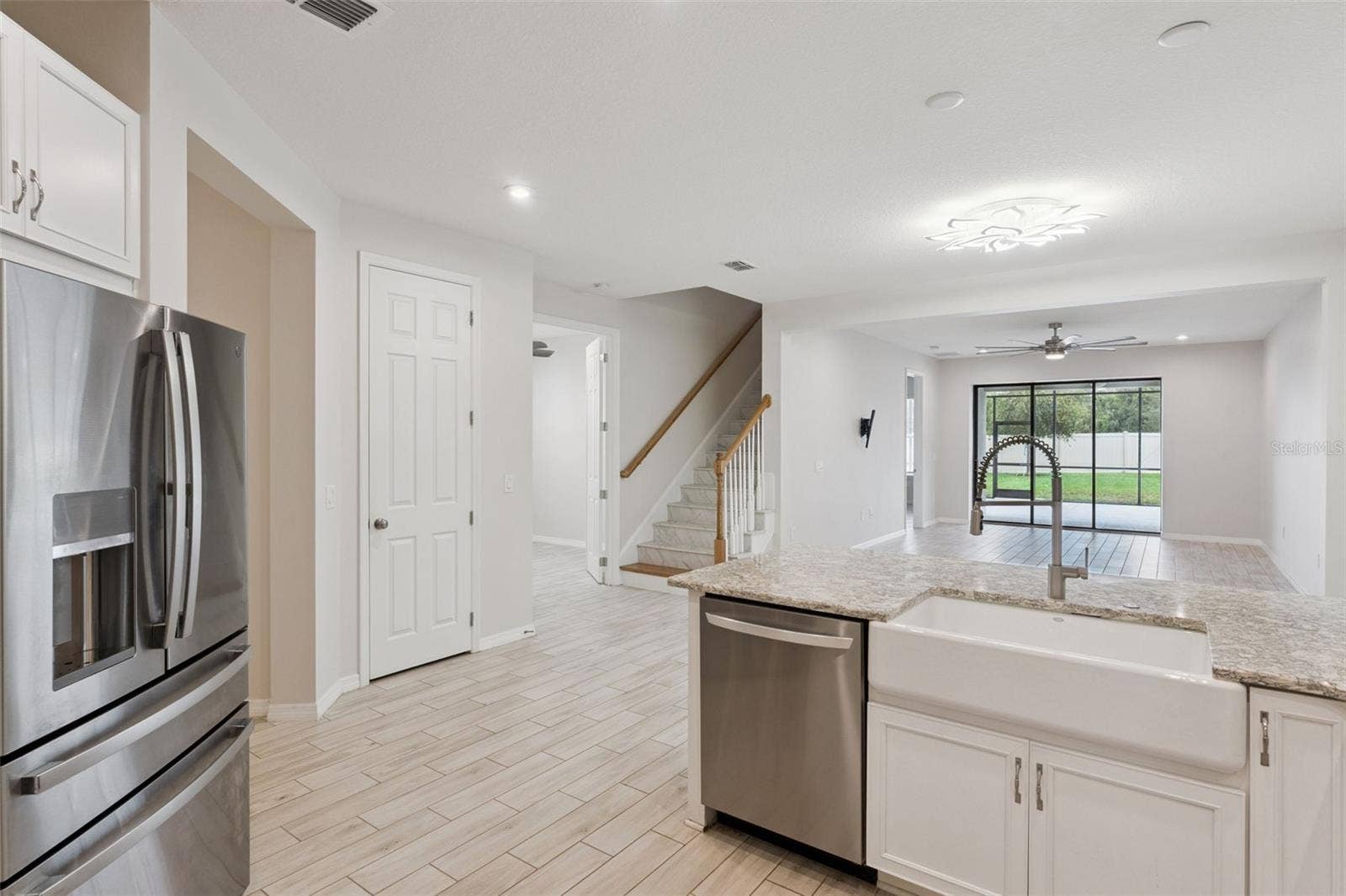 Kitchen & Open Living Area  Open-concept kitchen connects seamlessly with the main living area and features granite countertops, a farmhouse-style sink, stainless steel appliances, and a large peninsula overlooking the room and screened patio beyond.