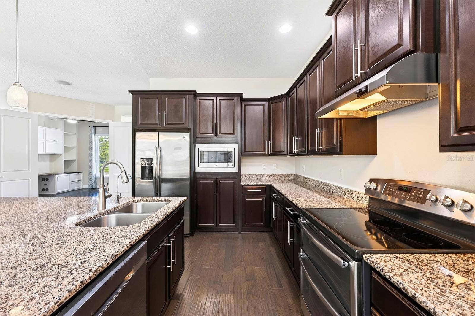 The gorgeous kitchen delivers incredible storage with rich cabinetry extending into the dining area, granite countertops, STAINLESS STEEL APPLIANCES, recessed and pendant lighting, and a large CENTER ISLAND with an extended breakfast table.