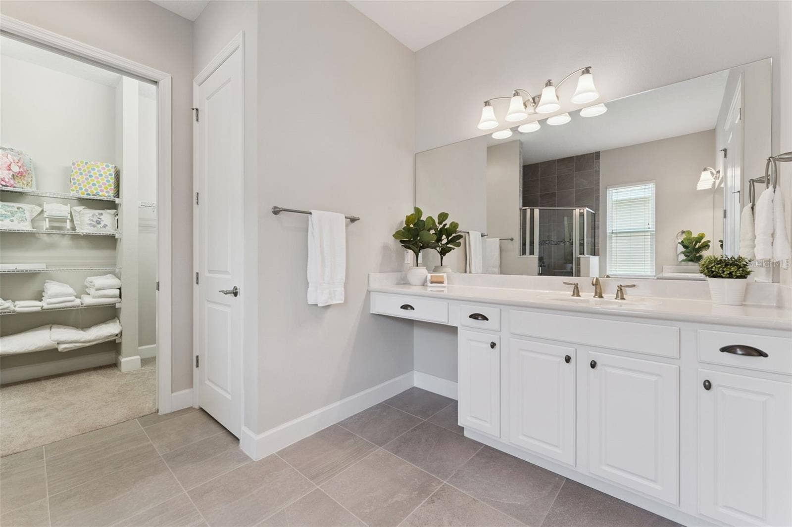 Primary Bathroom w/ separate vanities, glass enclosed walk-in shower & a spacious 14' x 5'6" walk-in closet