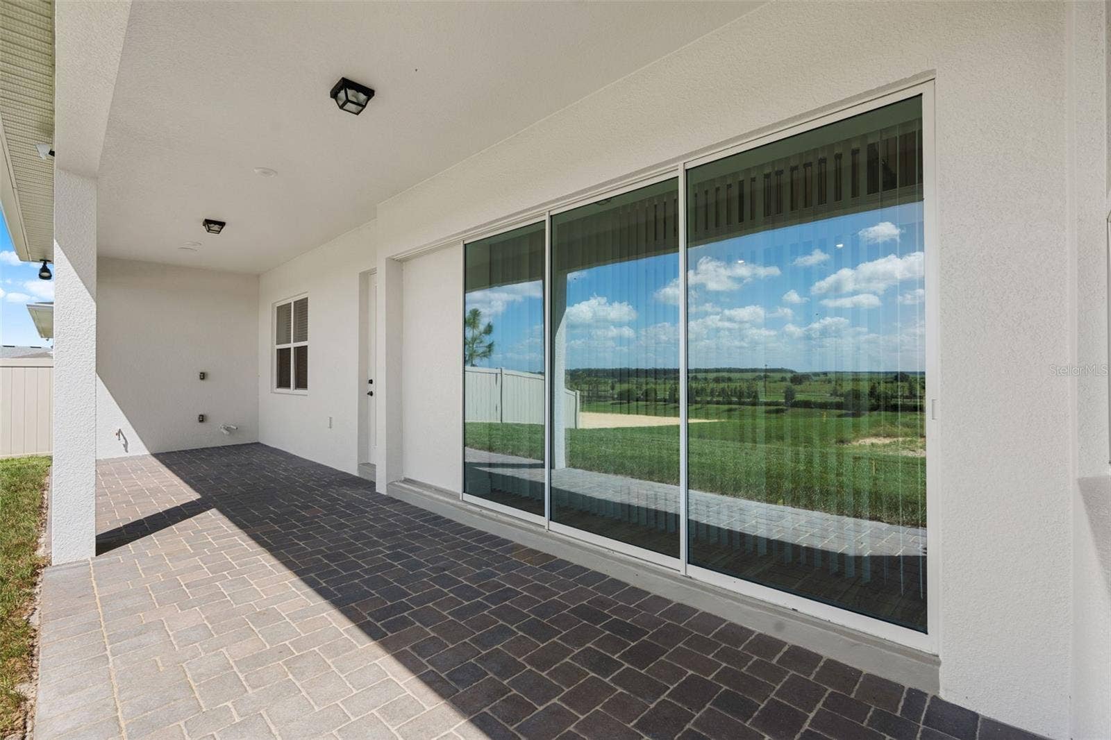 4617 GOLDEN BIRCH AVENUE, Clermont, FL 34714 Triple sliding glass doors open up to a paver lanai.