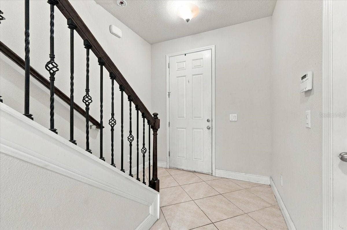 Bright foyer featuring tile flooring and an elegant wrought-iron stair railing