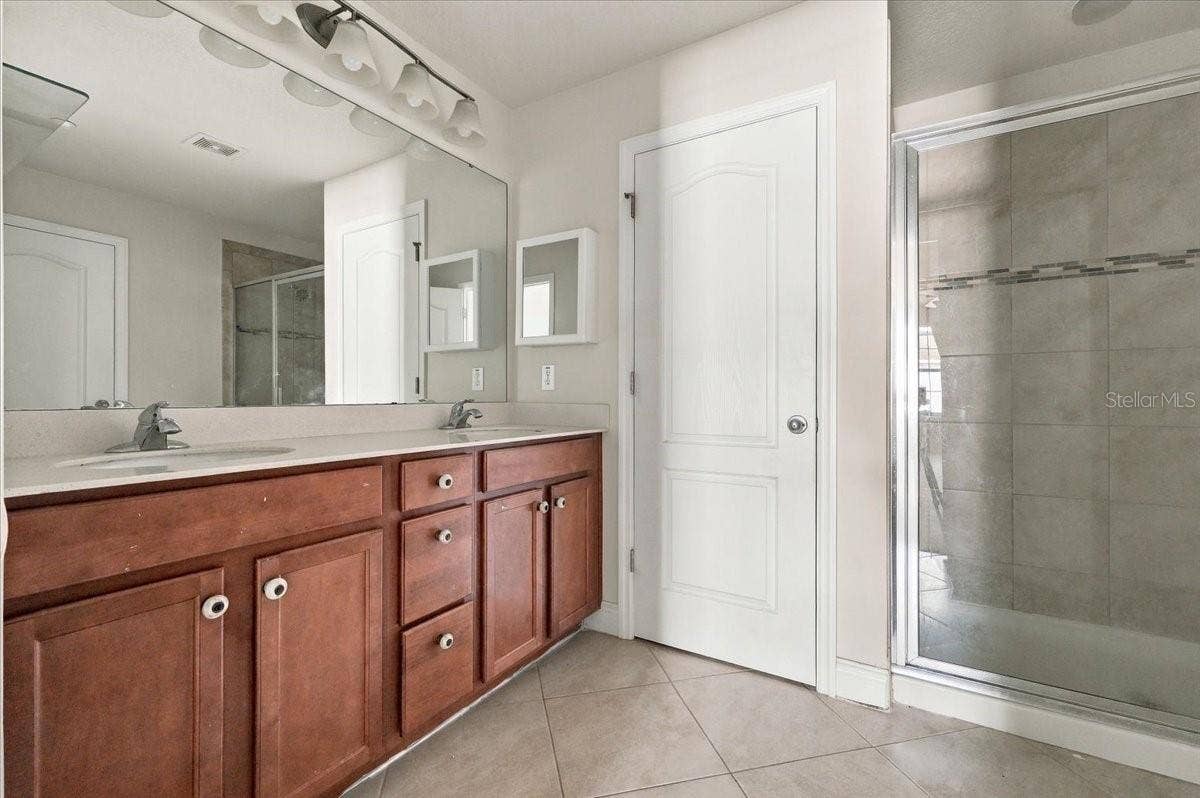 Primary ensuite bath featuring dual-sink vanity and a glass-enclosed walk-in shower