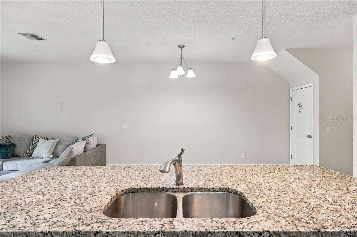 Granite kitchen island with double basin sink and stylish pendant lighting