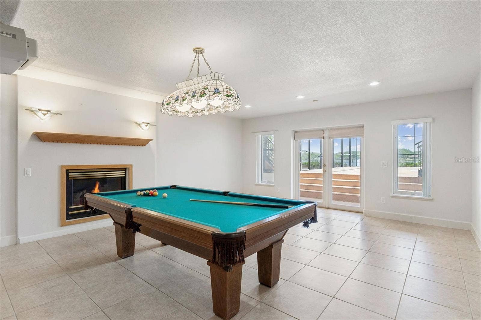 4301 DOWN POINT LANE, Windermere, FL 34786 Full basement living room with fireplace and French doors opening directly to the pool deck.