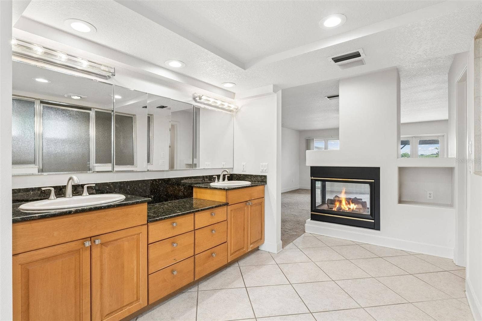 4301 DOWN POINT LANE, Windermere, FL 34786 Primary bathroom with dual vanities and a two-sided fireplace shared with the master bedroom.