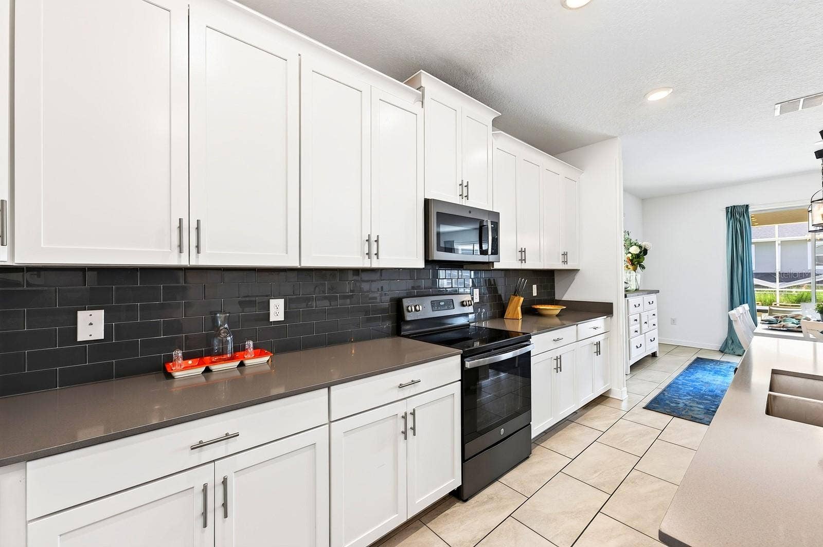 1045 LEADER STREET, Davenport, FL 33896 The spacious Kitchen is both stylish and functional, featuring 42-inch white cabinetry, QUARTZ COUNTERTOPS, a closet pantry, STAINLESS STEEL APPLIANCES and a sleek backsplash.