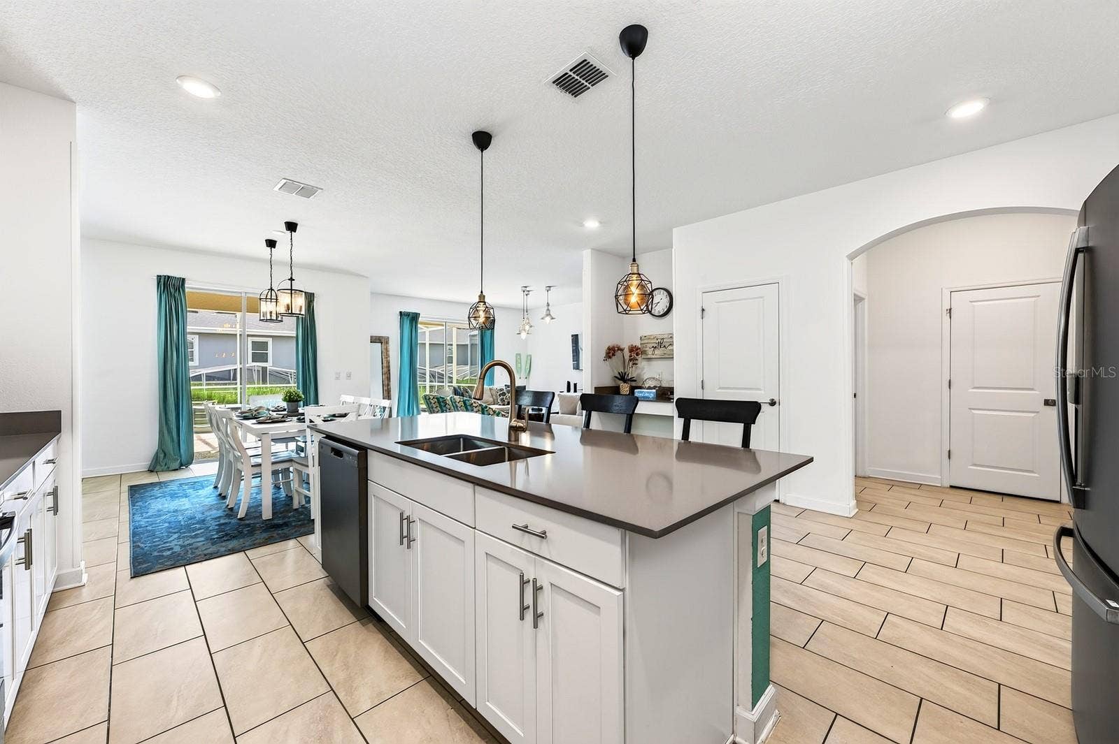 1045 LEADER STREET, Davenport, FL 33896 TWO SETS OF SLIDING GLASS DOORS bring in abundant natural light and create a seamless connection to the pool area, while CONTEMPORARY LIGHTING throughout adds a polished finishing touch.