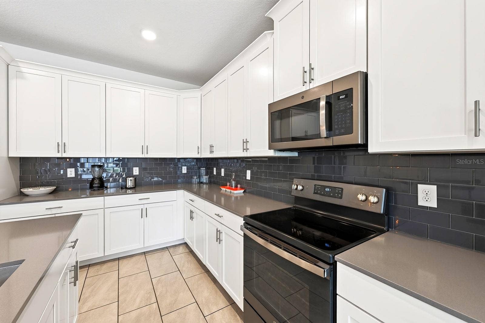 1045 LEADER STREET, Davenport, FL 33896 The spacious Kitchen is both stylish and functional, featuring 42-inch white cabinetry, QUARTZ COUNTERTOPS, a closet pantry, STAINLESS STEEL APPLIANCES and a sleek backsplash.
