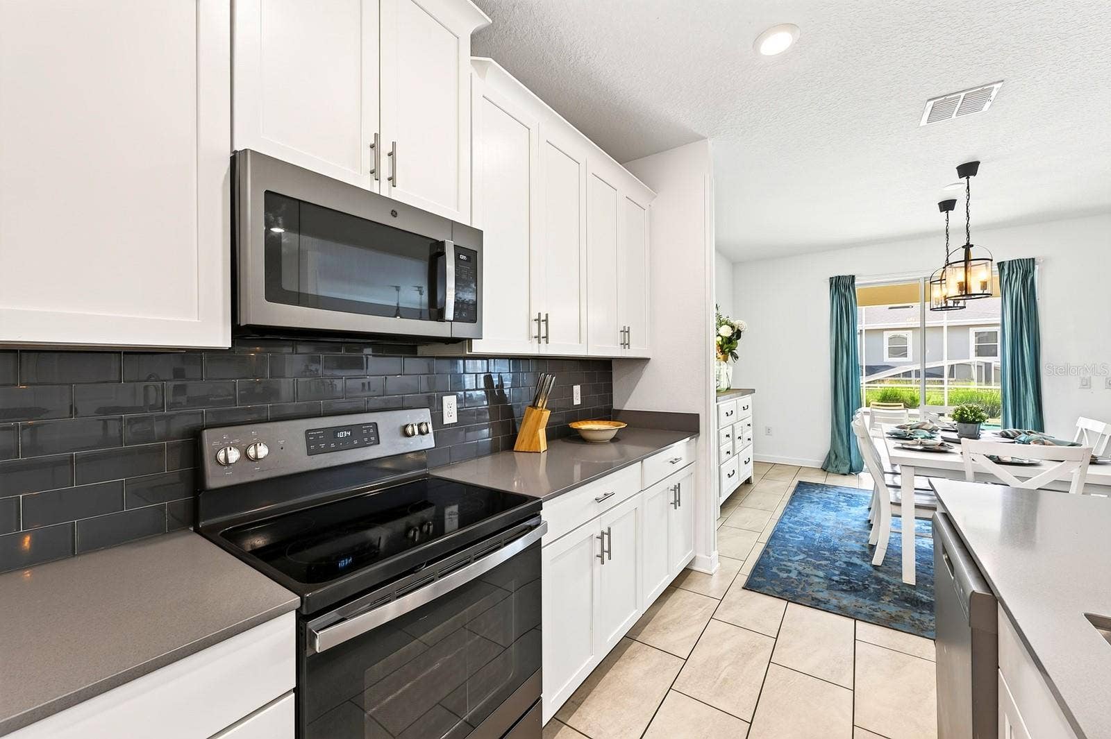 1045 LEADER STREET, Davenport, FL 33896 The spacious Kitchen is both stylish and functional, featuring 42-inch white cabinetry, QUARTZ COUNTERTOPS, a closet pantry, STAINLESS STEEL APPLIANCES and a sleek backsplash.