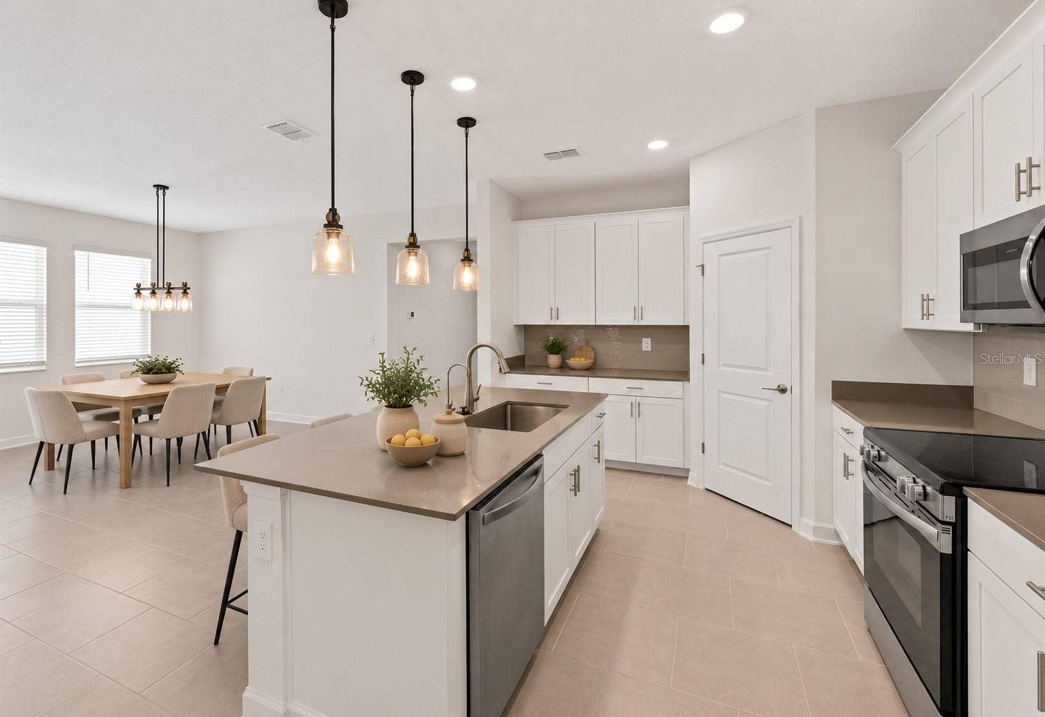 1874 FLOURISH AVENUE, Kissimmee, FL 34744 At the heart of the home, the kitchen features shaker style cabinetry, quartz countertops, stainless steel appliances, a tiled backsplash, pantry storage and a large island with breakfast bar seating beneath pendant lighting.