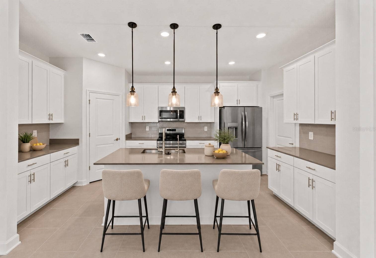 1874 FLOURISH AVENUE, Kissimmee, FL 34744 At the heart of the home, the kitchen features shaker style cabinetry, quartz countertops, stainless steel appliances, a tiled backsplash, pantry storage and a large island with breakfast bar seating beneath pendant lighting.