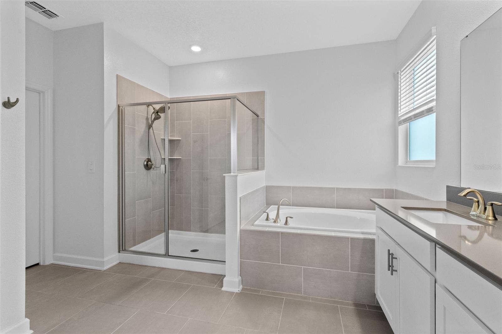 1874 FLOURISH AVENUE, Kissimmee, FL 34744 Tucked away at the rear of the home, the primary suite offers a generous walk in closet and a spacious private bathroom complete with quartz countertops, dual sinks, a soaking tub and separate shower. Direct access from the primary suite into the laundry room adds another layer of everyday convenience.