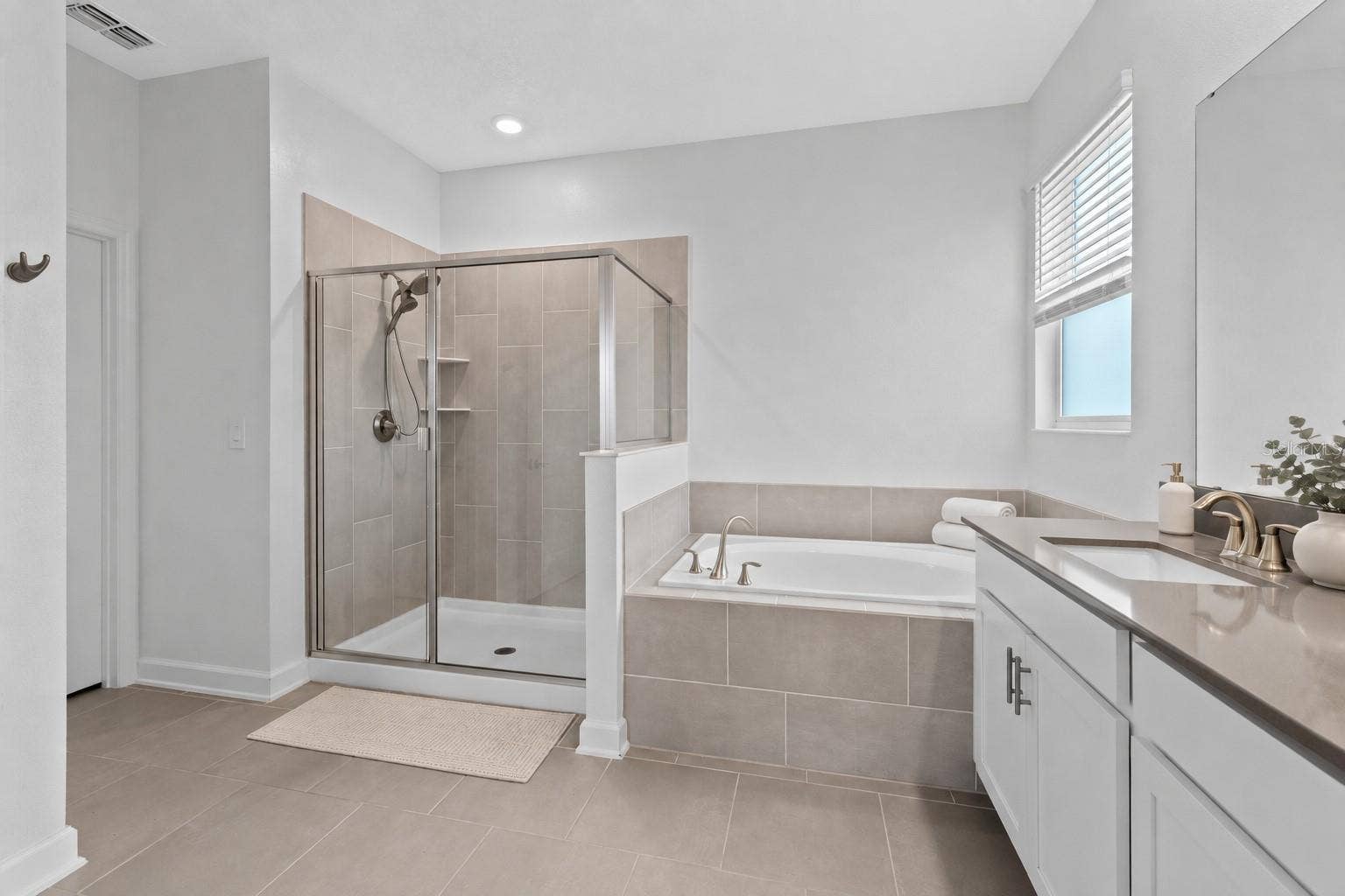 1874 FLOURISH AVENUE, Kissimmee, FL 34744 Tucked away at the rear of the home, the primary suite offers a generous walk in closet and a spacious private bathroom complete with quartz countertops, dual sinks, a soaking tub and separate shower. Direct access from the primary suite into the laundry room adds another layer of everyday convenience.