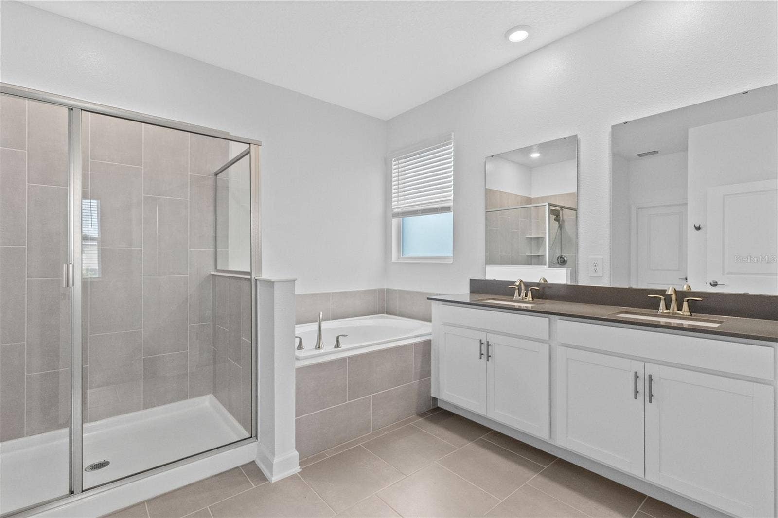 1874 FLOURISH AVENUE, Kissimmee, FL 34744 Tucked away at the rear of the home, the primary suite offers a generous walk in closet and a spacious private bathroom complete with quartz countertops, dual sinks, a soaking tub and separate shower. Direct access from the primary suite into the laundry room adds another layer of everyday convenience.