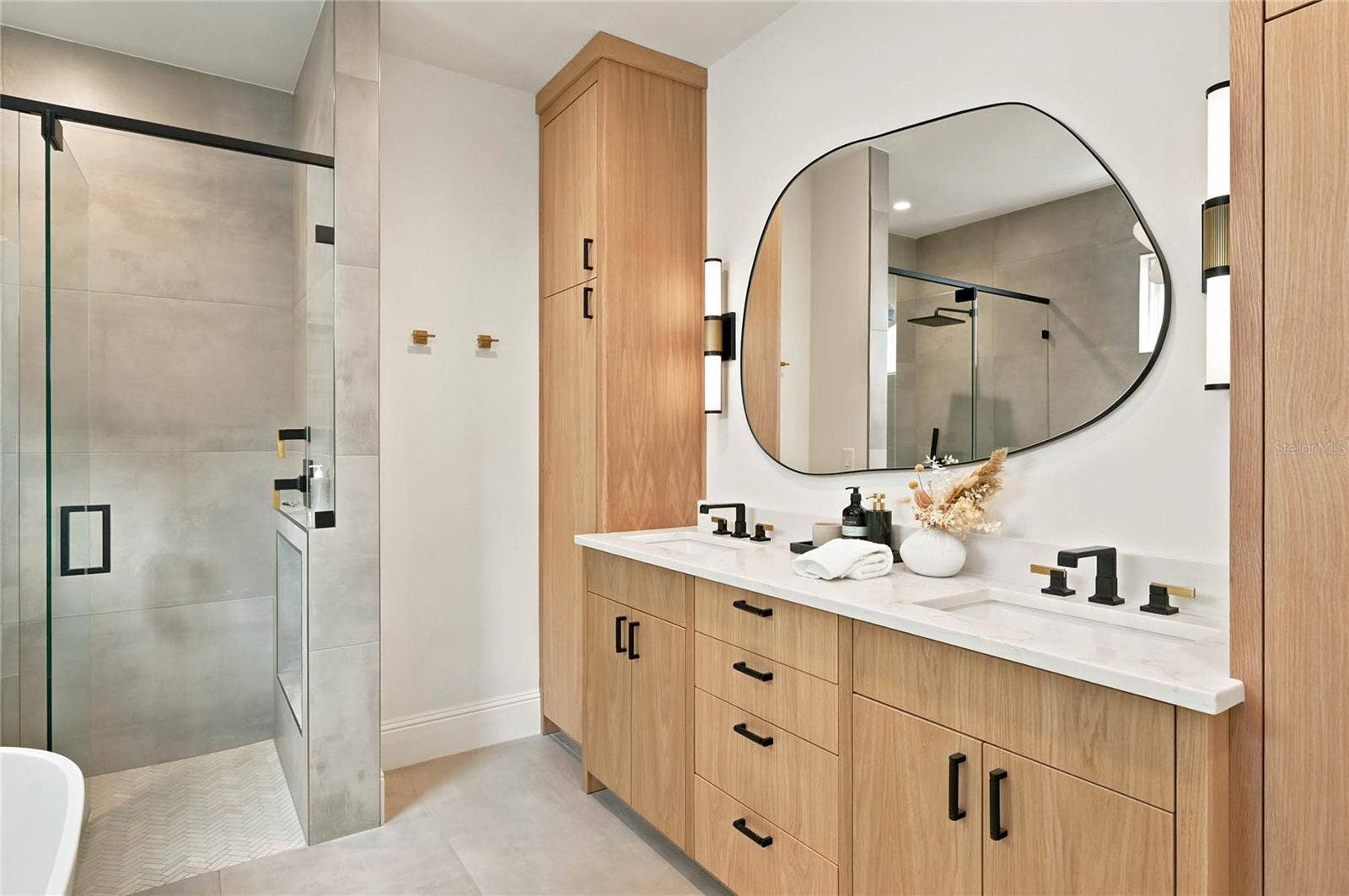 1707 ASHER LANE, Orlando, FL 32803 pairs warm wood cabinetry with clean contemporary finishes featuring a double vanity accented by mixed black and brass fixtures. A statement mirror & lighting add an artful touch to the serene, sophisticated space.