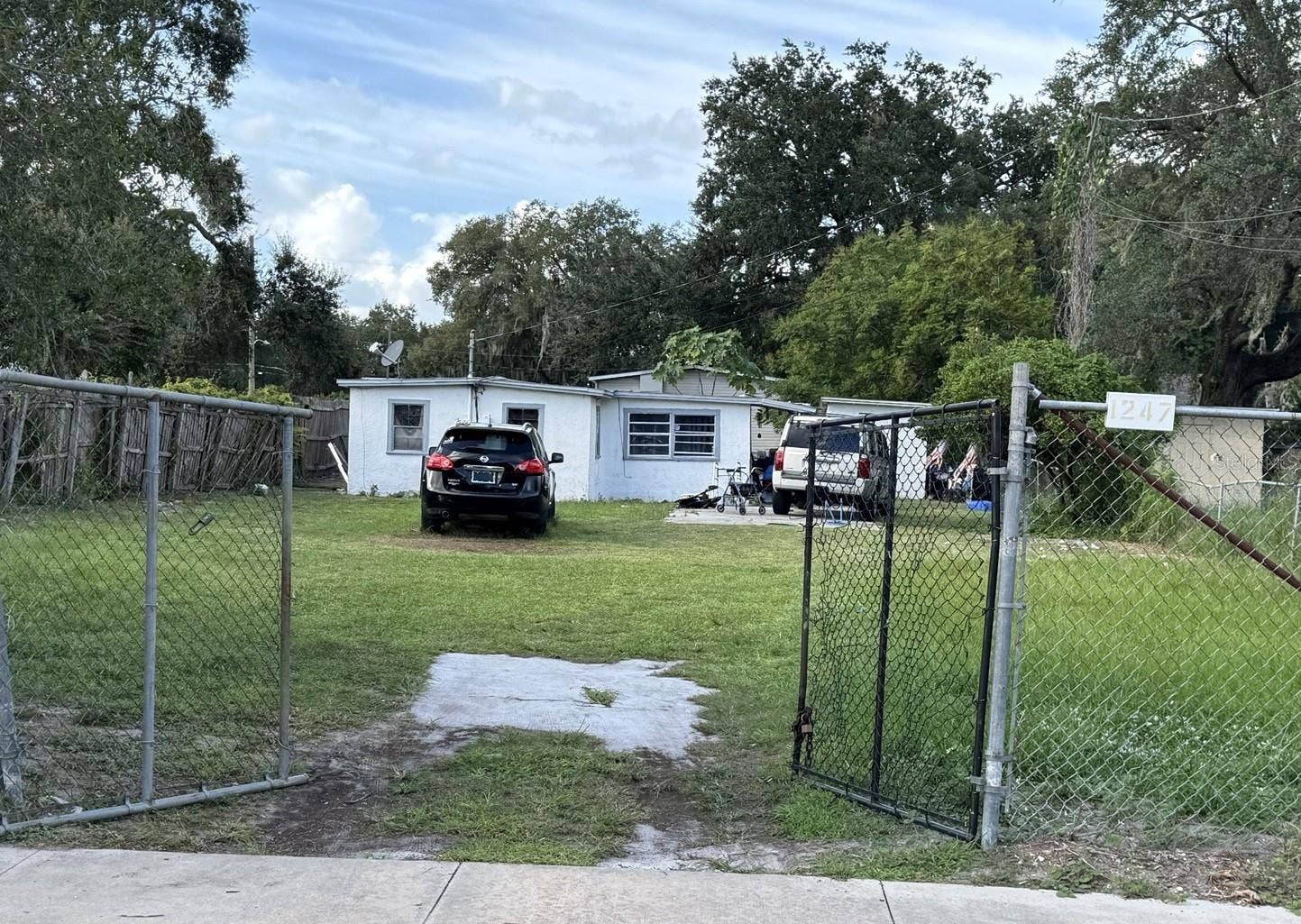 1239 19TH STREET, Orlando, FL 32805 1247 19th Street wide exterior view, the third contiguous preproperty - showing the fenced lot and setback from the street