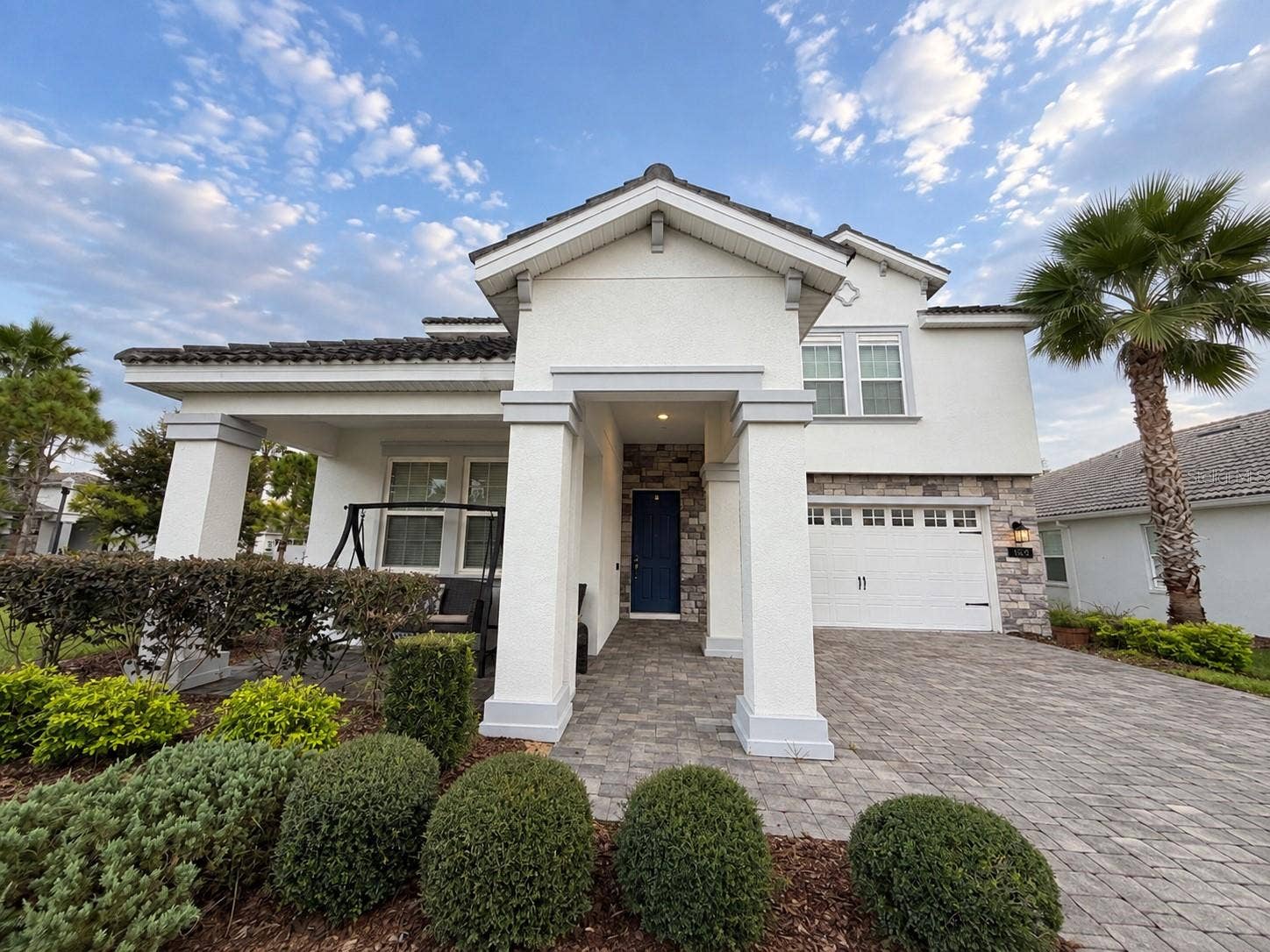 1516 BUNKER DRIVE, Davenport, FL 33896 Inviting front elevation featuring a covered porch, stone accents and paver driveway.