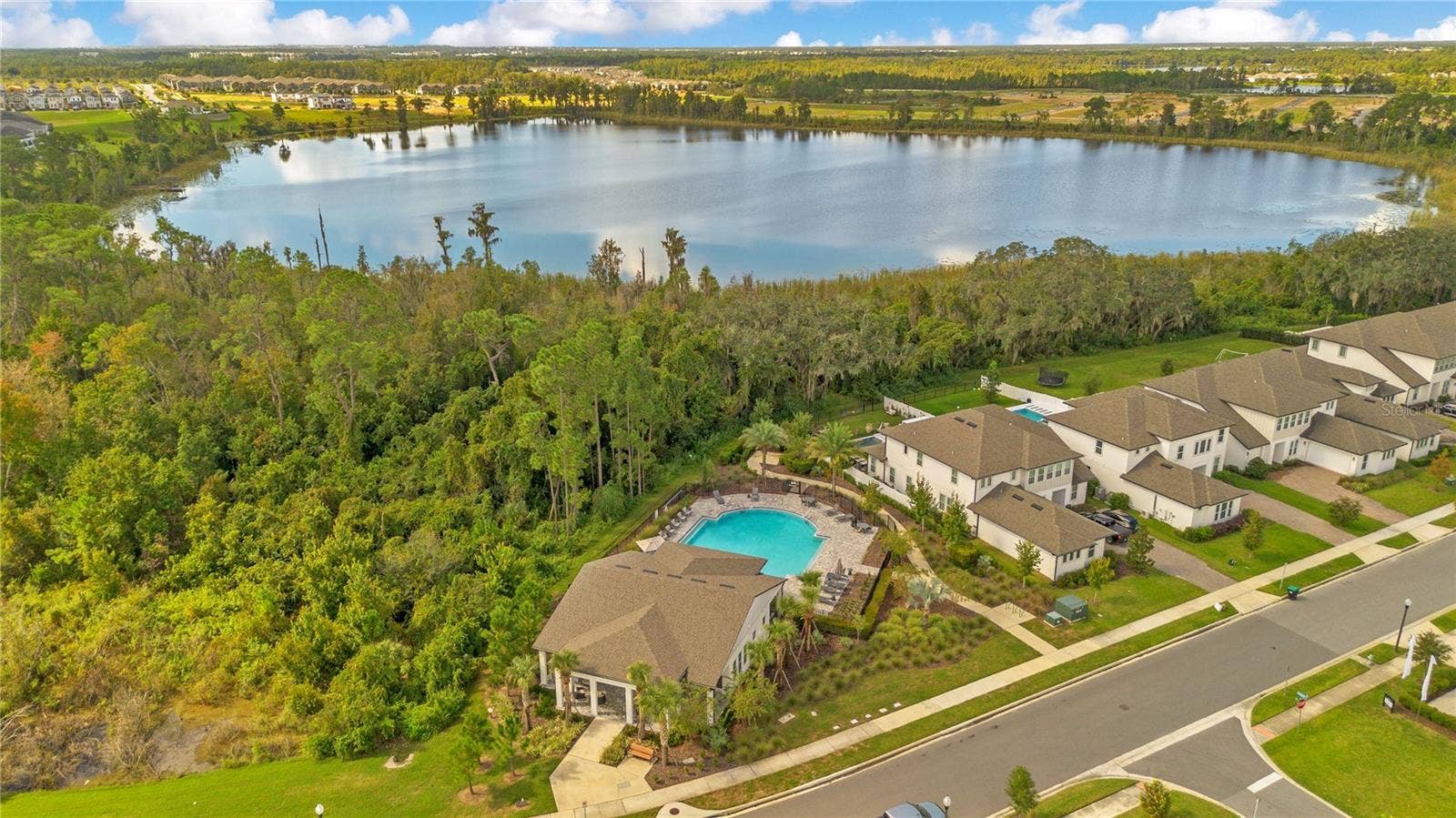 17600 LAKE STAR ROAD, Winter Garden, FL 34787 Aerial view of the community amenity area with a pool, clubhouse and lake backdrop.