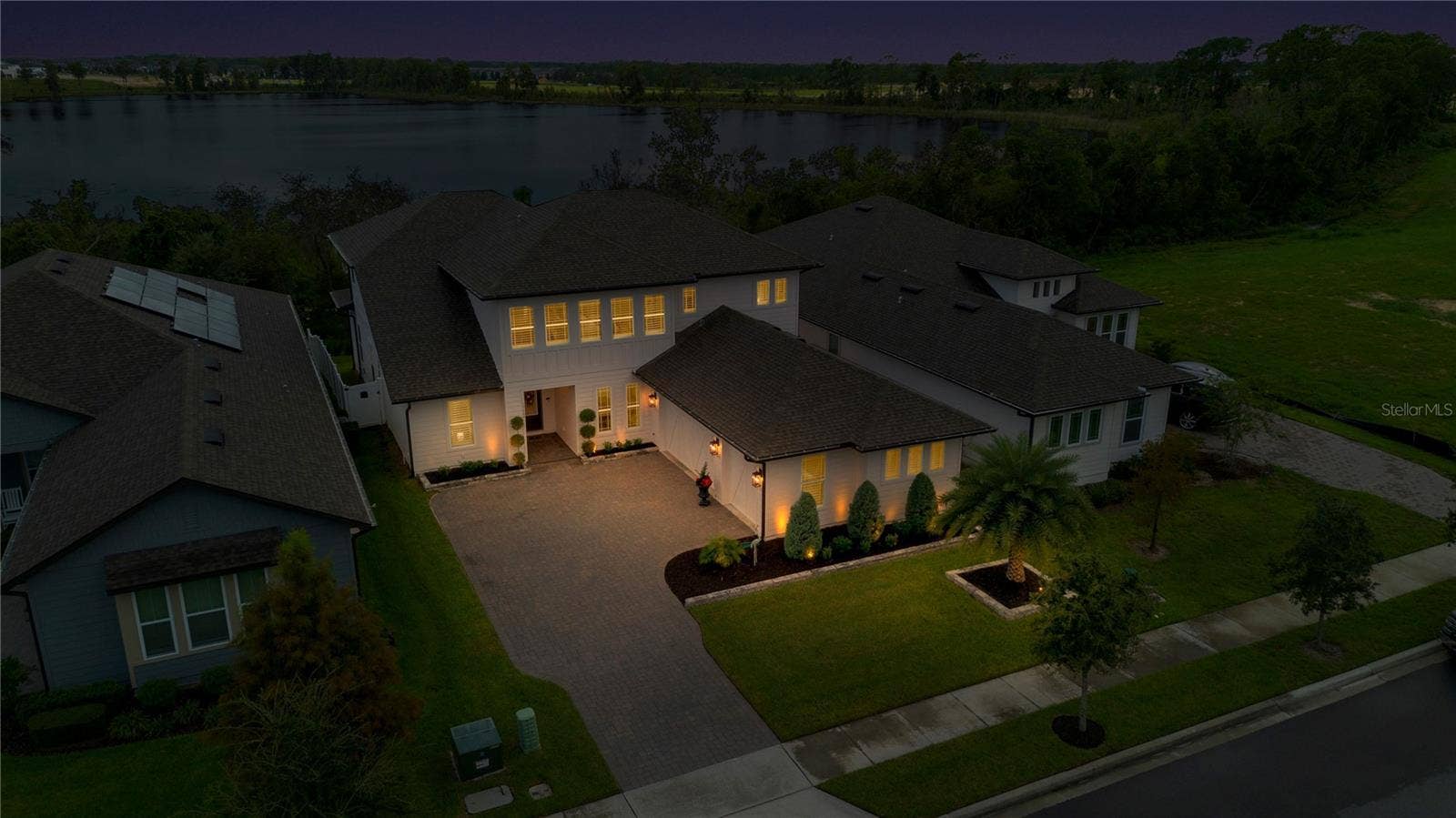 17600 LAKE STAR ROAD, Winter Garden, FL 34787 Twilight aerial showcases the home with the lake visible beyond the surrounding trees.