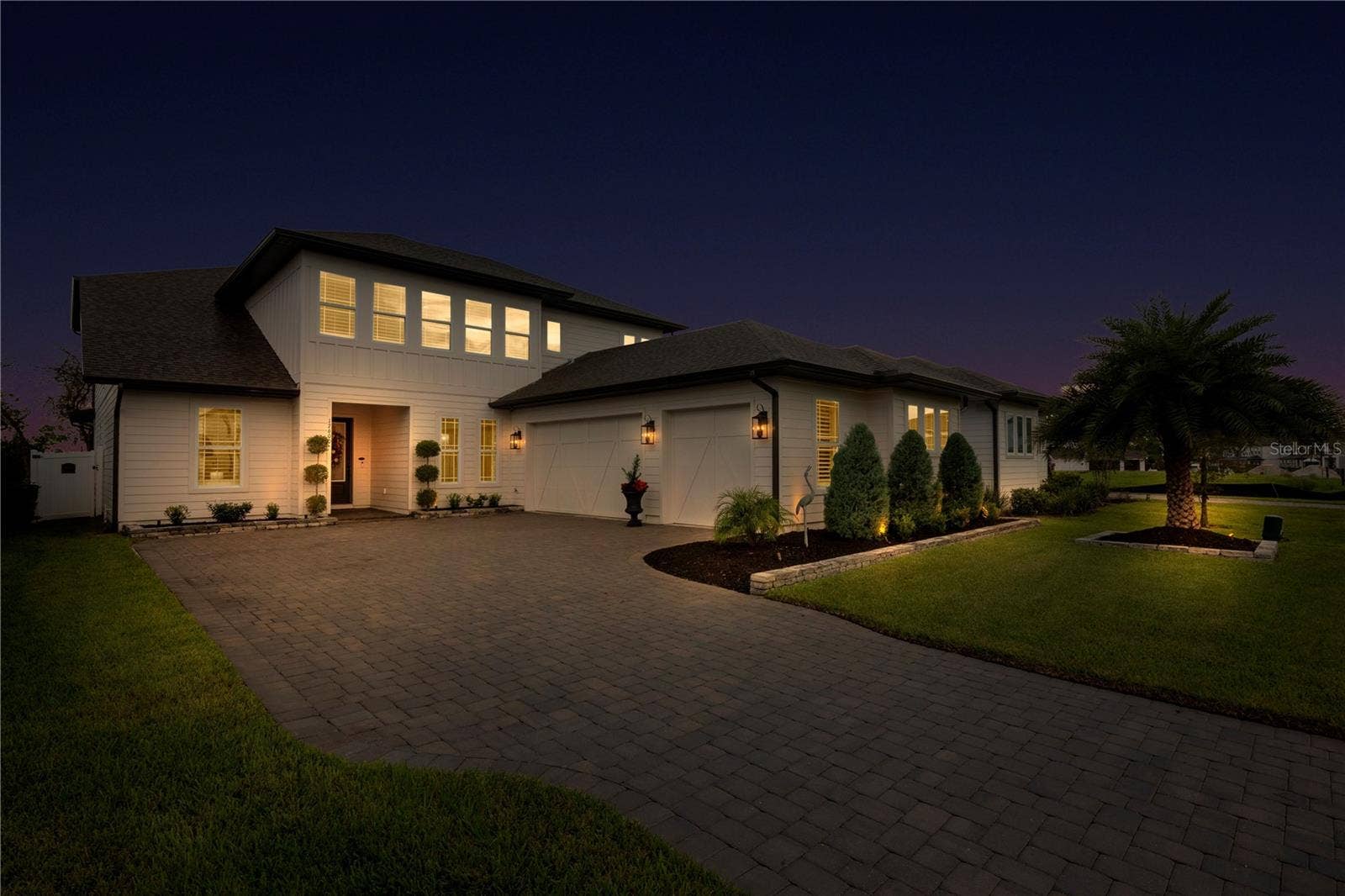 17600 LAKE STAR ROAD, Winter Garden, FL 34787 Evening exterior highlights illuminated garden beds and the landscaped front lawn.