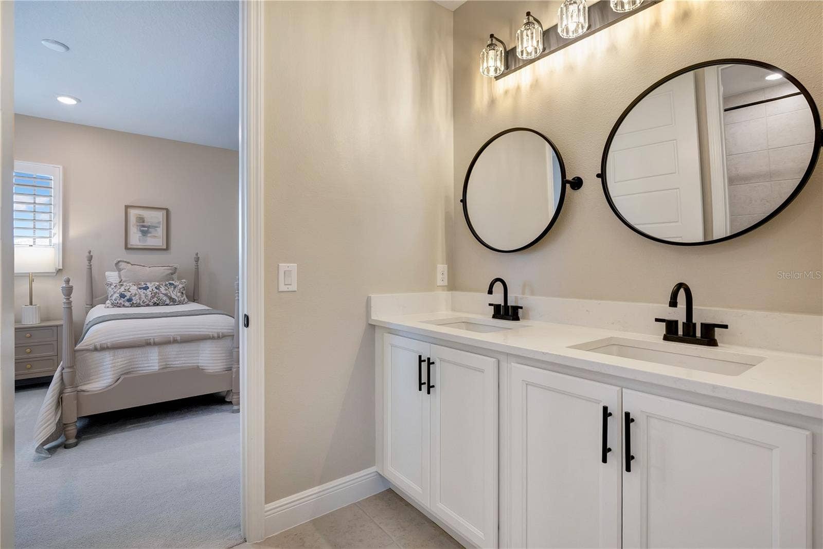 17600 LAKE STAR ROAD, Winter Garden, FL 34787 Double-sink vanity featuring white cabinetry, contrasting black fixtures and coordinating round mirrors.