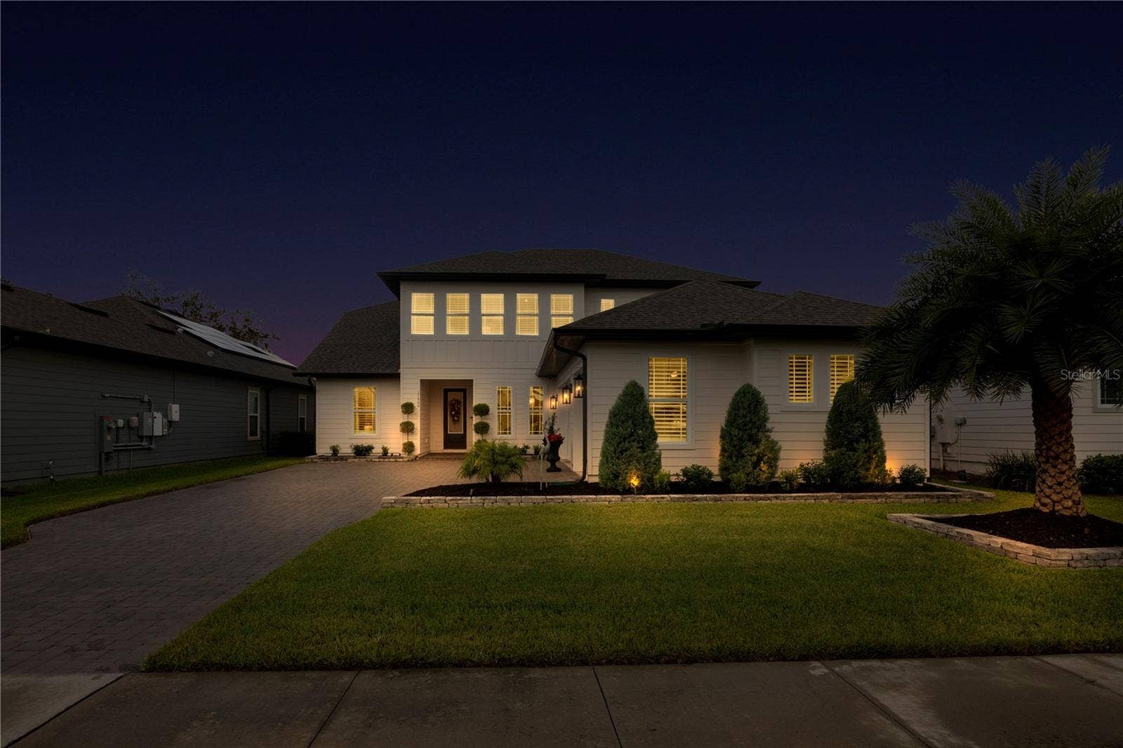 17600 LAKE STAR ROAD, Winter Garden, FL 34787 Twilight view of the paver driveway and front entrance with warm exterior lighting.