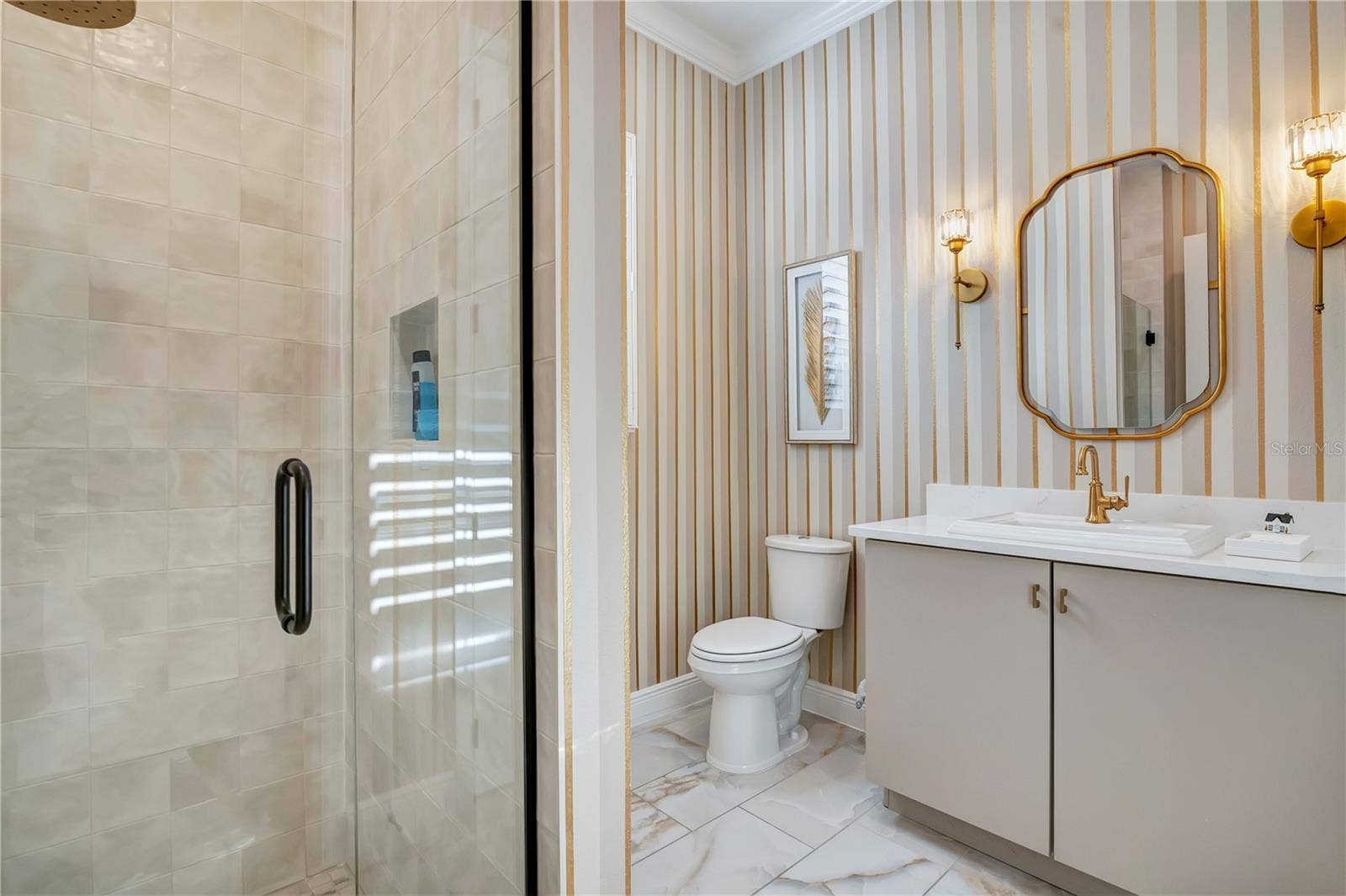 17600 LAKE STAR ROAD, Winter Garden, FL 34787 Designer bathroom with a glass-enclosed shower, striped accent wall and gold-tone fixtures.