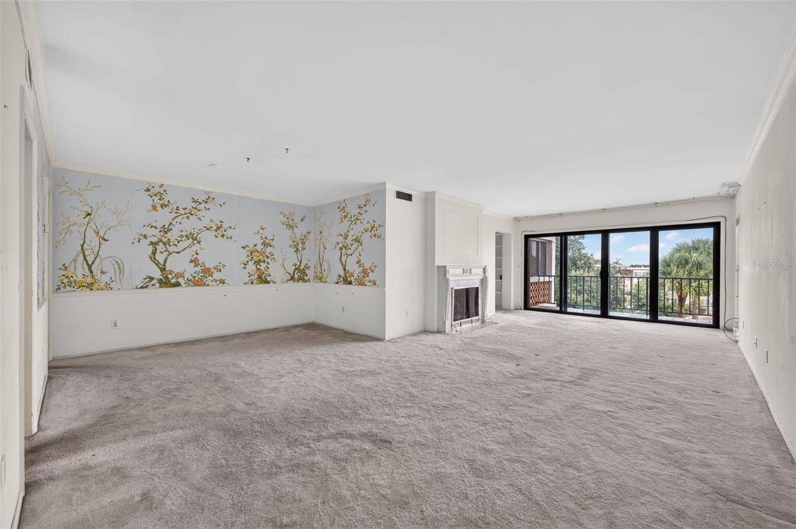 100 S INTERLACHEN AVENUE, #401, Winter Park, FL 32789 A spacious, light-filled living and dining area features a classic fireplace, walls of glass, and beautiful treetop views, offering endless possibilities to create a stunning modern retreat.