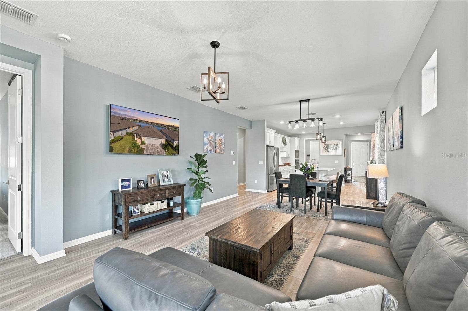 9260 BALLASTER POINTE LOOP, Parrish, FL 34219 Great View of Living to Dining to Kitchen. Showing Luxury Vinyl Plank Flooring throughout the living areas and updated lighting.