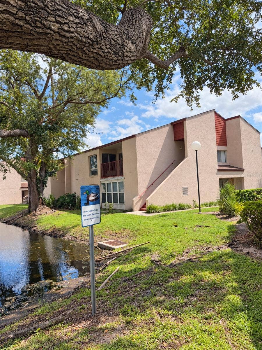 2527 CITRUS CLUB LANE, #3904, Orlando, FL 32839 Exterior view framed by oak trees.