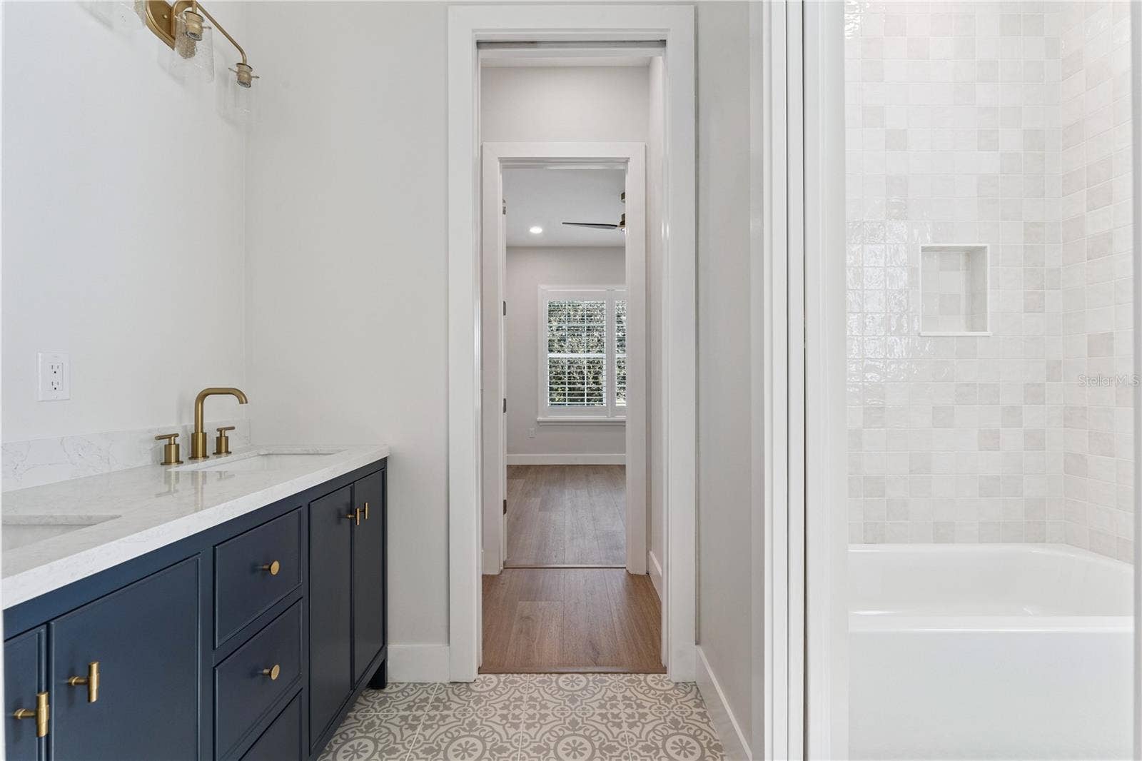 3456 FAIRWAY LANE, Orlando, FL 32804 A navy double vanity pairs with patterned flooring and a tub-and-shower combination.