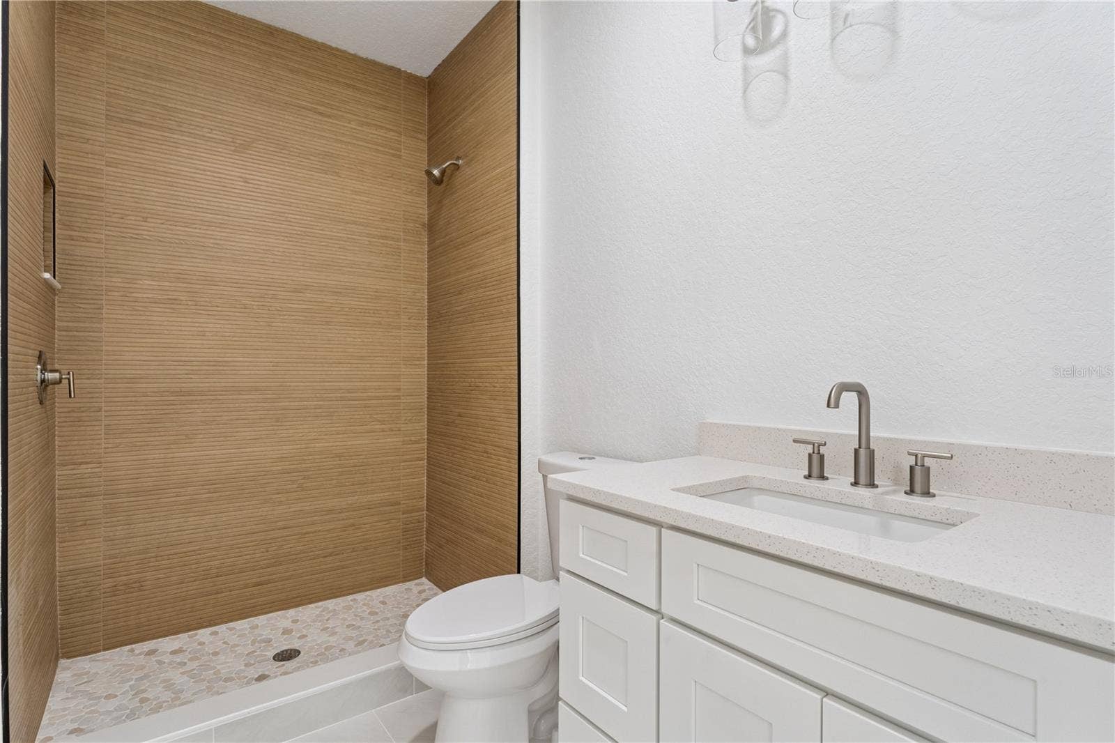 3456 FAIRWAY LANE, Orlando, FL 32804 This bathroom features a white vanity and a walk-in shower with wood-look wall tile.