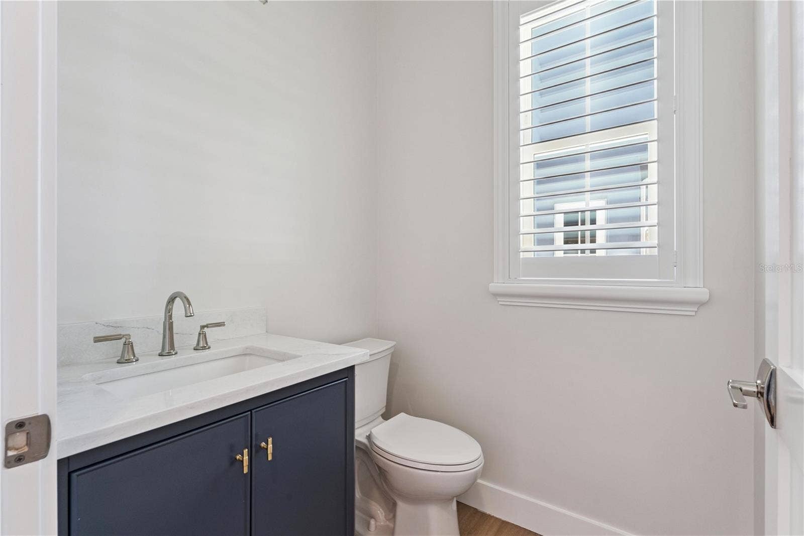 3456 FAIRWAY LANE, Orlando, FL 32804 A navy vanity, light countertop, and shuttered window give this powder room a crisp finish.