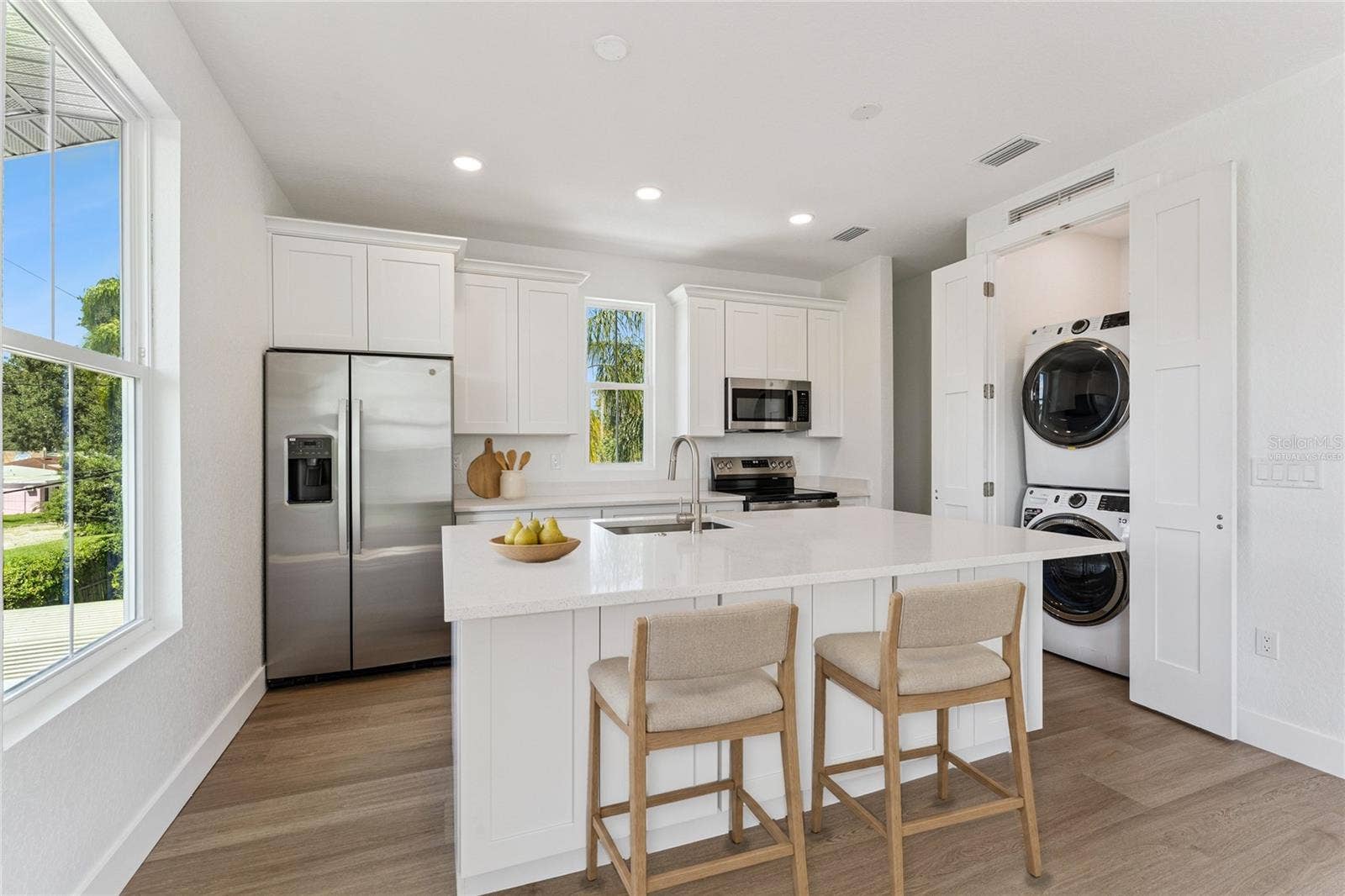 3456 FAIRWAY LANE, Orlando, FL 32804 Virtually Staged - The guest-suite kitchen includes a white island, stainless steel appliances, and a stacked washer and dryer.