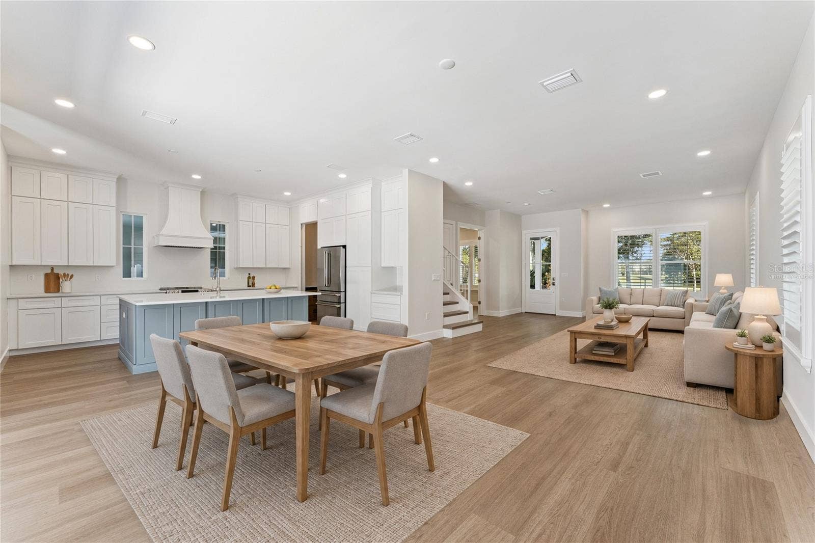 3456 FAIRWAY LANE, Orlando, FL 32804 Virtually Staged - An open living area connects to the kitchen, with a blue island and coordinated white cabinetry.
