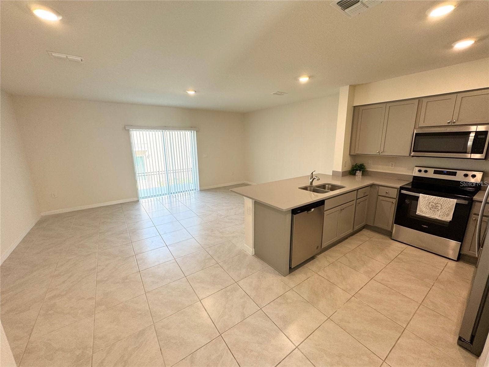 View of living room, sliding doors, dining area and kitchen.