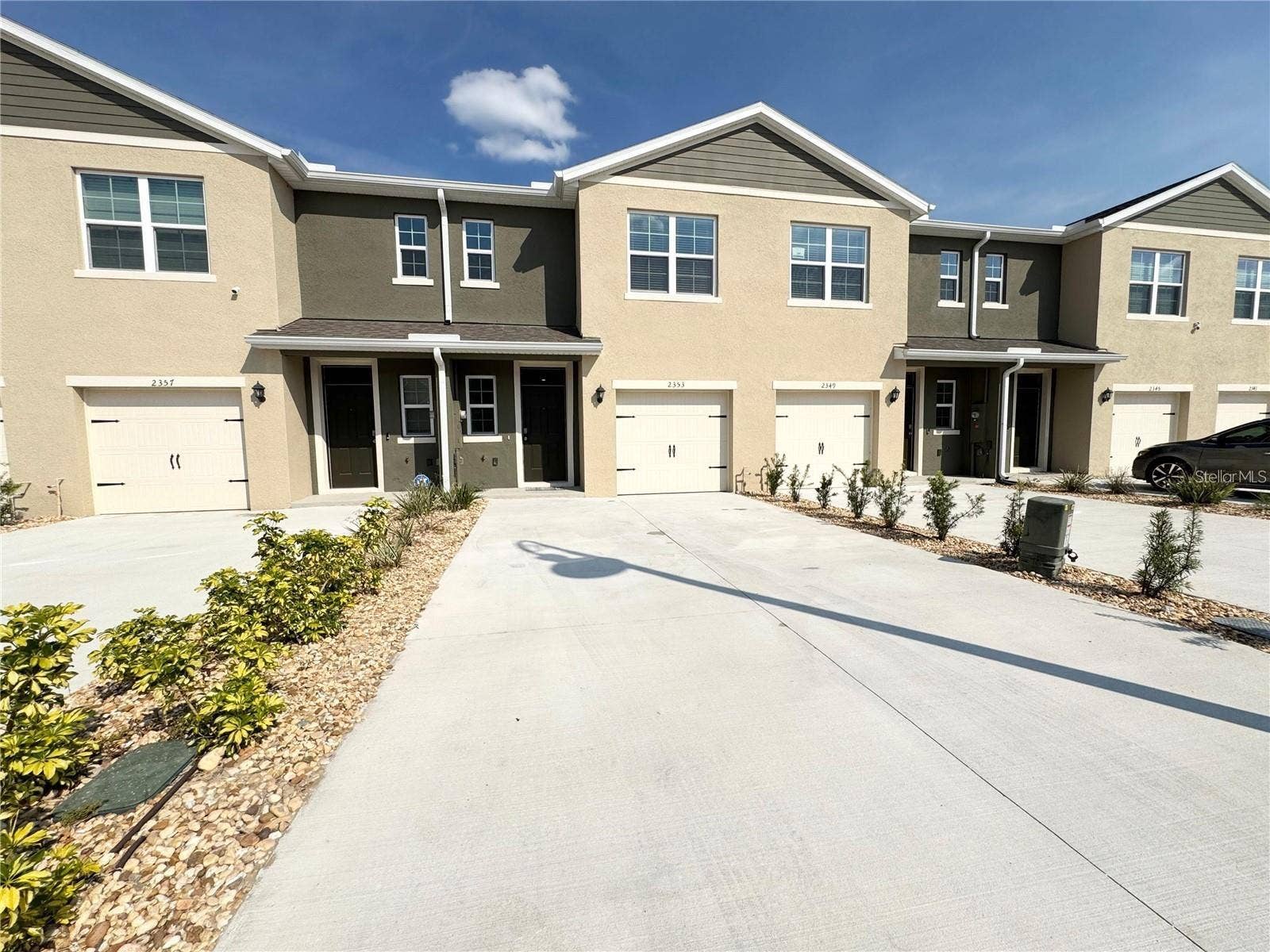 View of long driveway, entrance and one car garage.