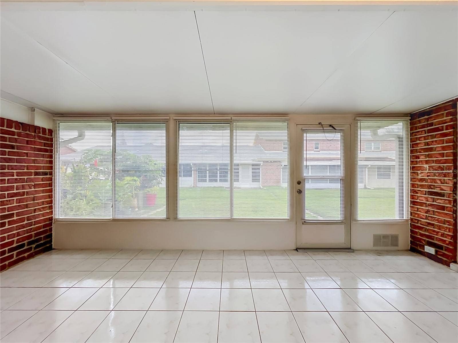 1225 CARRIAGE LANE, #1, Orlando, FL 32807 Spacious enclosed Florida room with tile flooring and wall-to-wall windows.