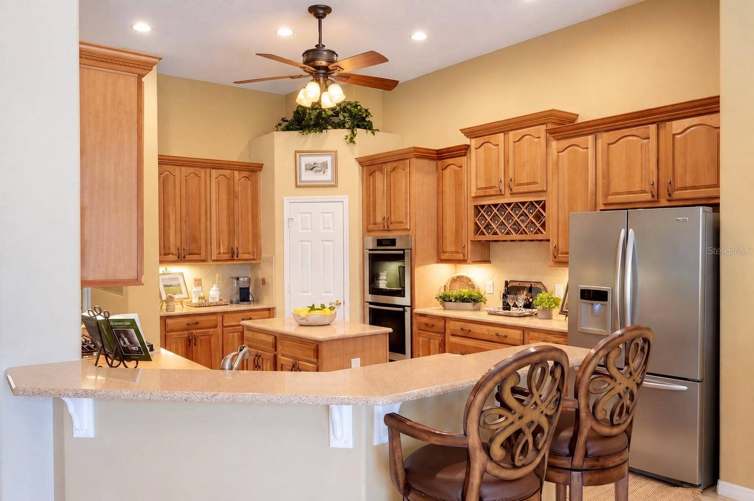 CENTER ISLAND, EXPANSIVE BREAKFAST BAR WITH SEATING, BUILT-IN DOUBLE OVENS, STAINLESS STEEL APPLIANCES, CUSTOM WINE RACK, AND CONVENIENT PANTRY!