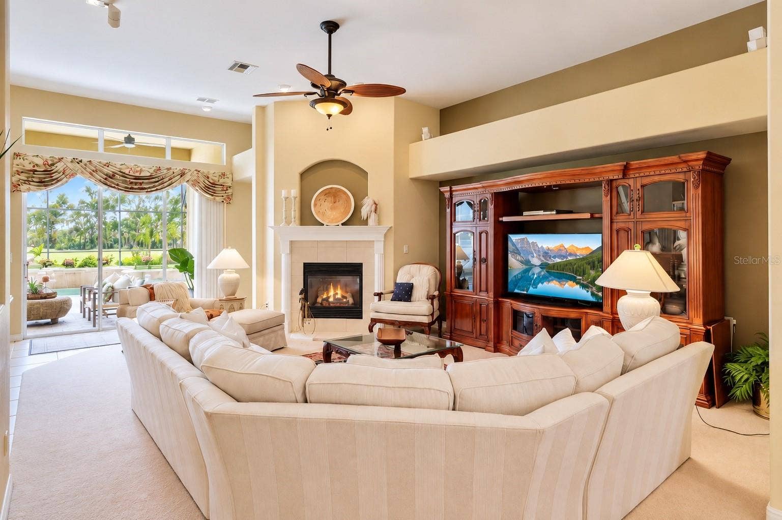 STUNNING, SPACIOUS FAMILY ROOM FEATURING SOARING CEILINGS, A BEAUTIFUL GAS FIREPLACE, ELEGANT ARCHITECTURAL DETAILS, AND ABUNDANT NATURAL LIGHT! Expansive sliding glass doors provide picturesque views of the sparkling pool and lush tropical landscaping while creating a seamless flow to the covered lanai. The perfect gathering space for cozy evenings by the fireplace, entertaining guests, and enjoying Florida's indoor-outdoor lifestyle!