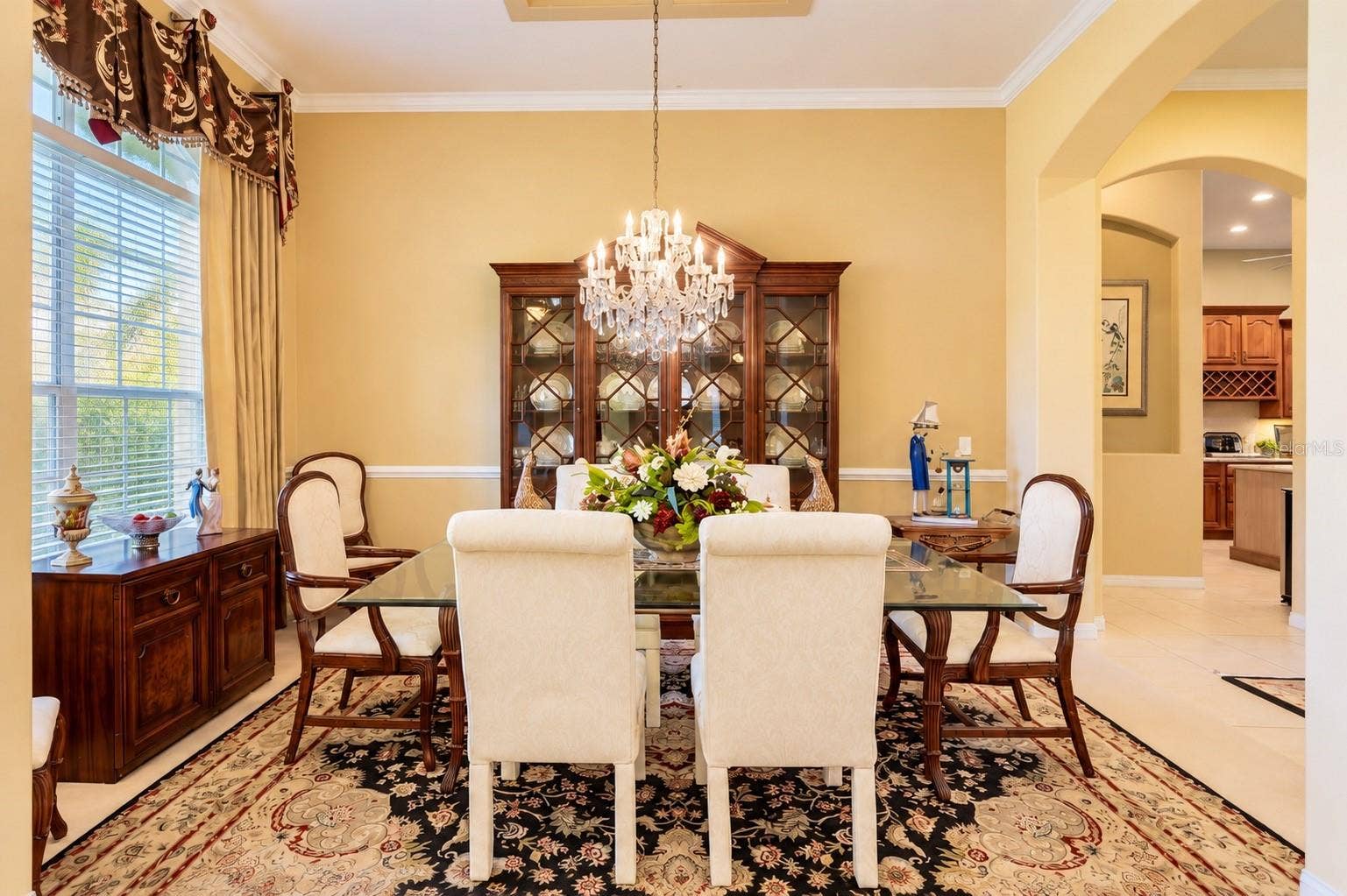 ELEGANT FORMAL DINING ROOM FEATURING SOARING CEILINGS, BEAUTIFUL CROWN MOLDING, and DECORATIVE CHAIR RAIL! A large window fills the room with natural light, while graceful architectural archways create an inviting flow to the kitchen, making this the perfect space for hosting holiday gatherings, special celebrations, and memorable dinners with family and friends!
