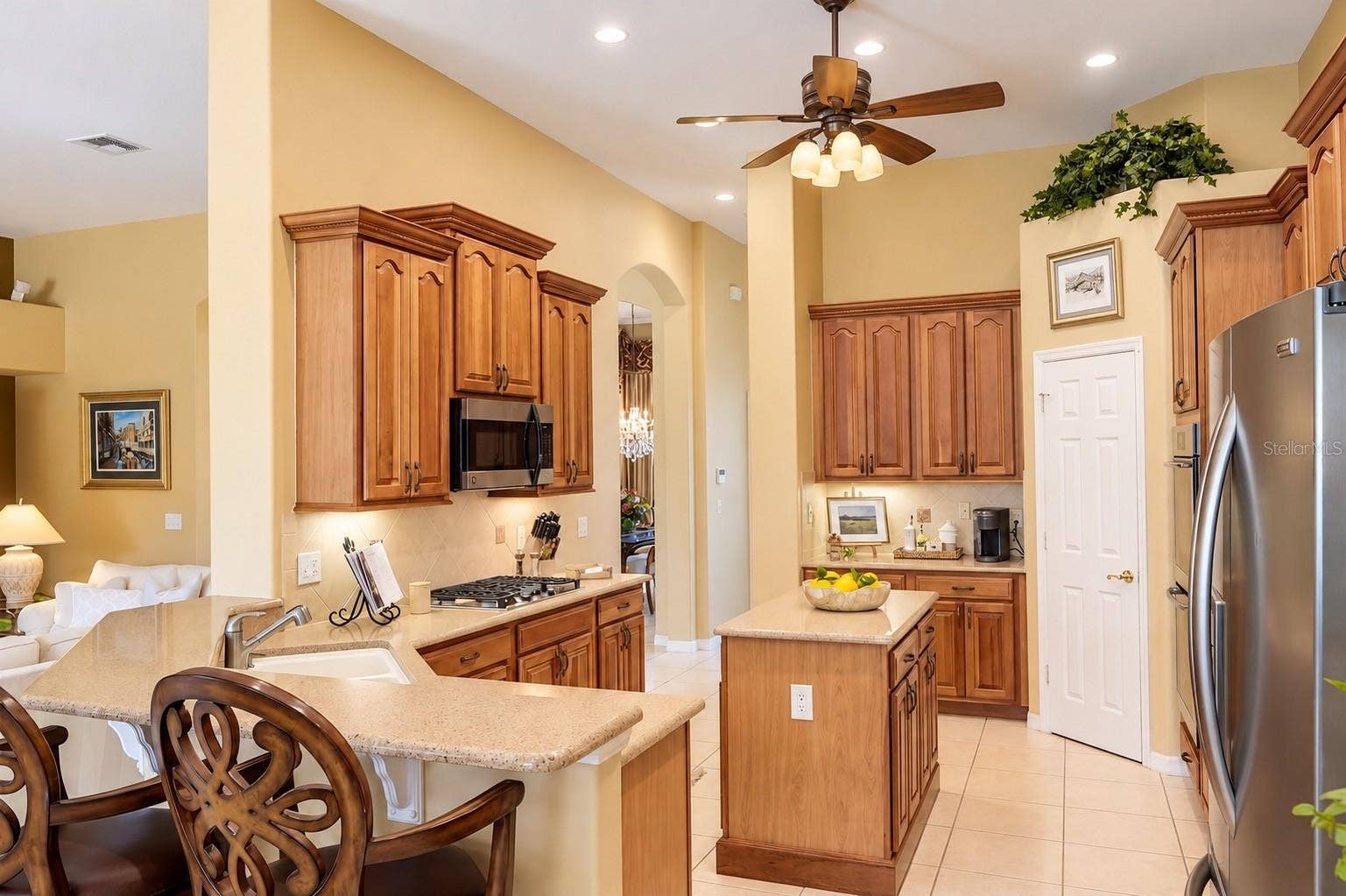 BEAUTIFULLY DESIGNED, SPACIOUS KITCHEN FEATURING SOARING CEILINGS, GORGEOUS WOOD CABINETRY, ABUNDANT COUNTER SPACE, AND STAINLESS STEEL APPLIANCES! Enjoy a CENTER ISLAND, BREAKFAST BAR WITH ADDITIONAL SEATING, GAS COOKTOP, UNDER-CABINET LIGHTING, AND RECESSED LIGHTING!