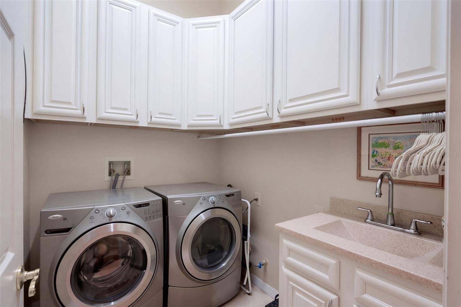 CUSTOM LAUNDRY ROOM FEATURING BEAUTIFUL CABINETRY, AMPLE STORAGE SPACE, AND A CONVENIENT UTILITY SINK FOR ADDED FUNCTIONALITY!