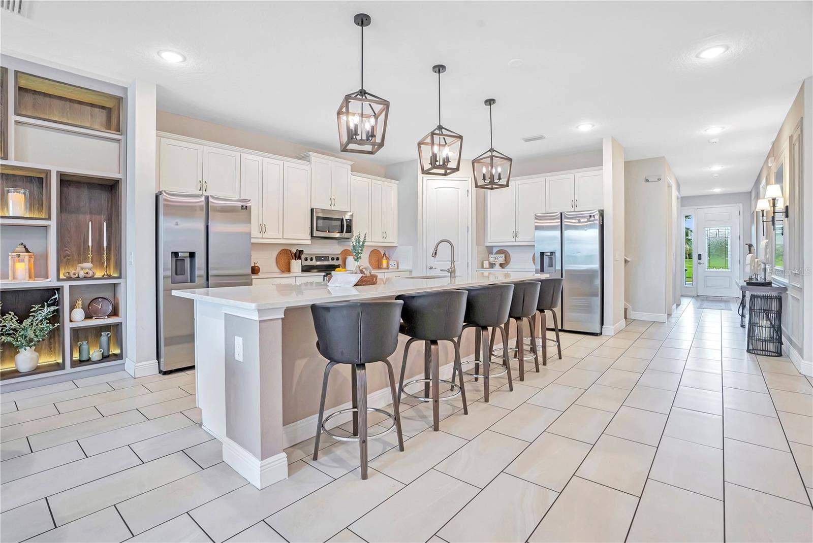 7704 WESTLAND DRIVE, Kissimmee, FL 34747 An impressive open-concept kitchen featuring an oversized island, elegant cabinetry, designer pendant lighting, and generous seating for gathering and entertaining