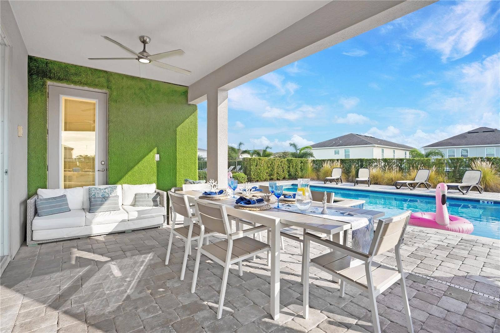 7704 WESTLAND DRIVE, Kissimmee, FL 34747 A spacious covered lanai with ceiling fans, outdoor dining, and poolside views