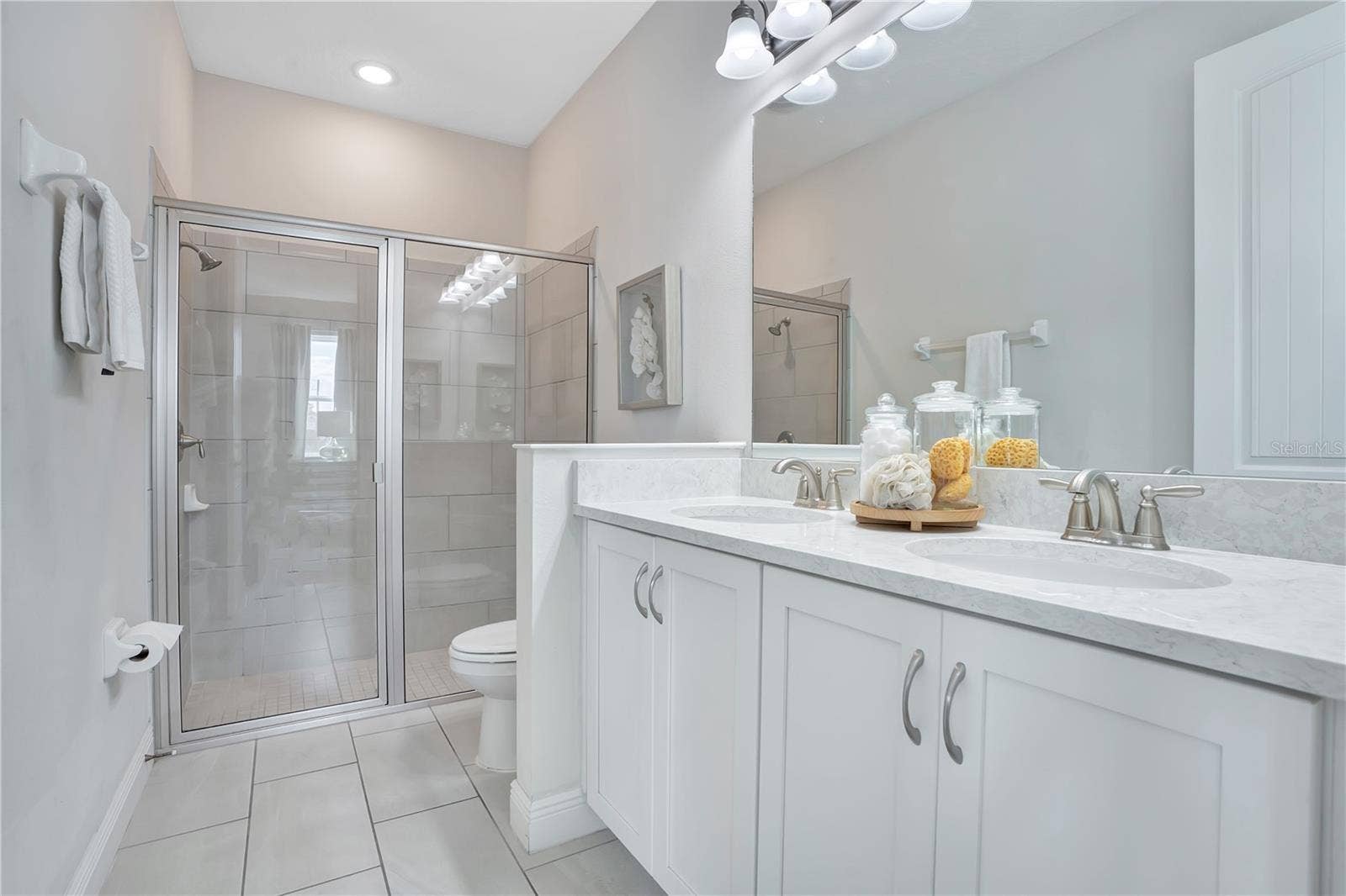 7704 WESTLAND DRIVE, Kissimmee, FL 34747 Bright, elegant en-suite bath to 1st floor primary with a glass-enclosed shower and generous vanity
