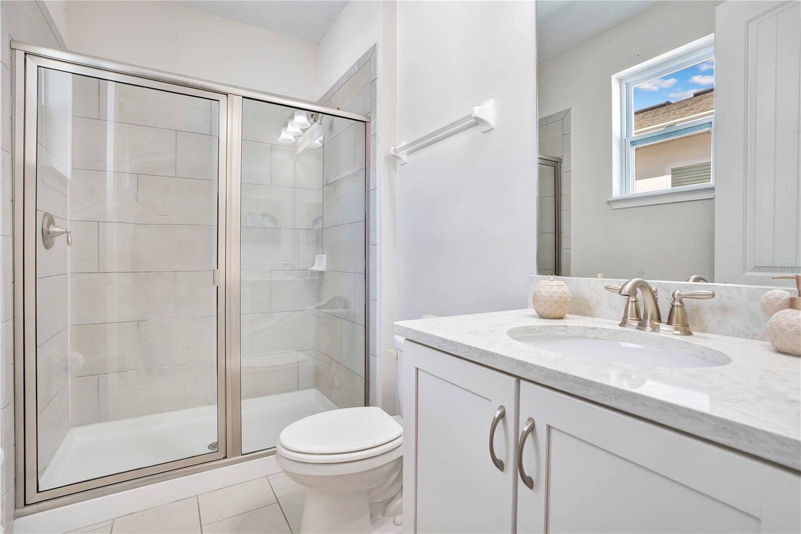 7704 WESTLAND DRIVE, Kissimmee, FL 34747 A private en-suite bath with contemporary fixtures and a glass-enclosed shower