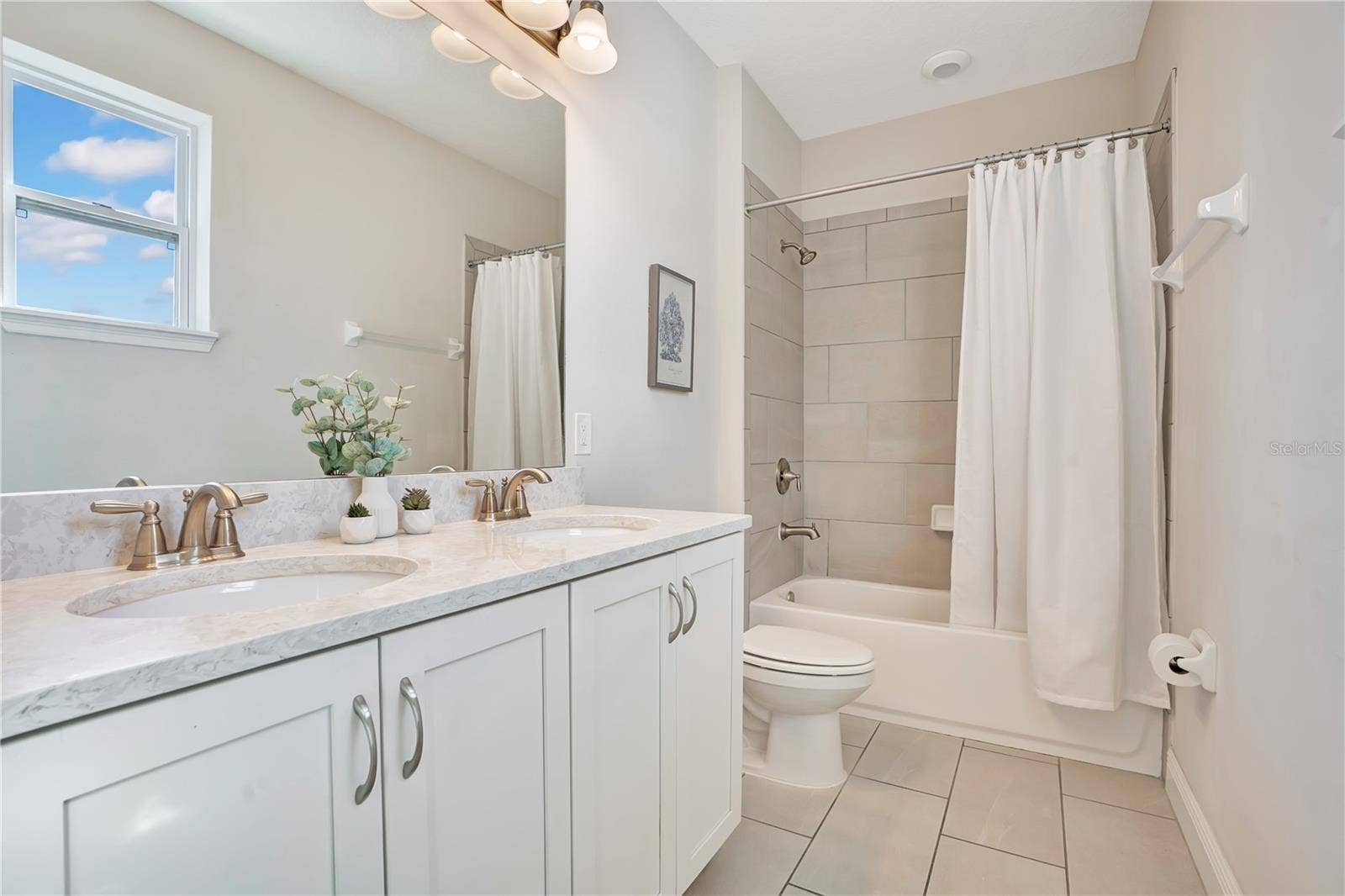 7704 WESTLAND DRIVE, Kissimmee, FL 34747 A beautifully finished en-suite bathroom with a spacious vanity and tub-shower combination