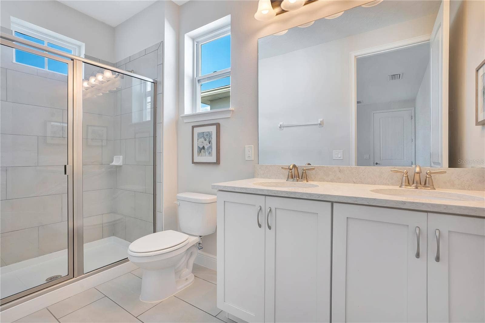 7704 WESTLAND DRIVE, Kissimmee, FL 34747 A beautifully appointed en-suite bath to upstairs primary with a spacious vanity and glass-enclosed shower